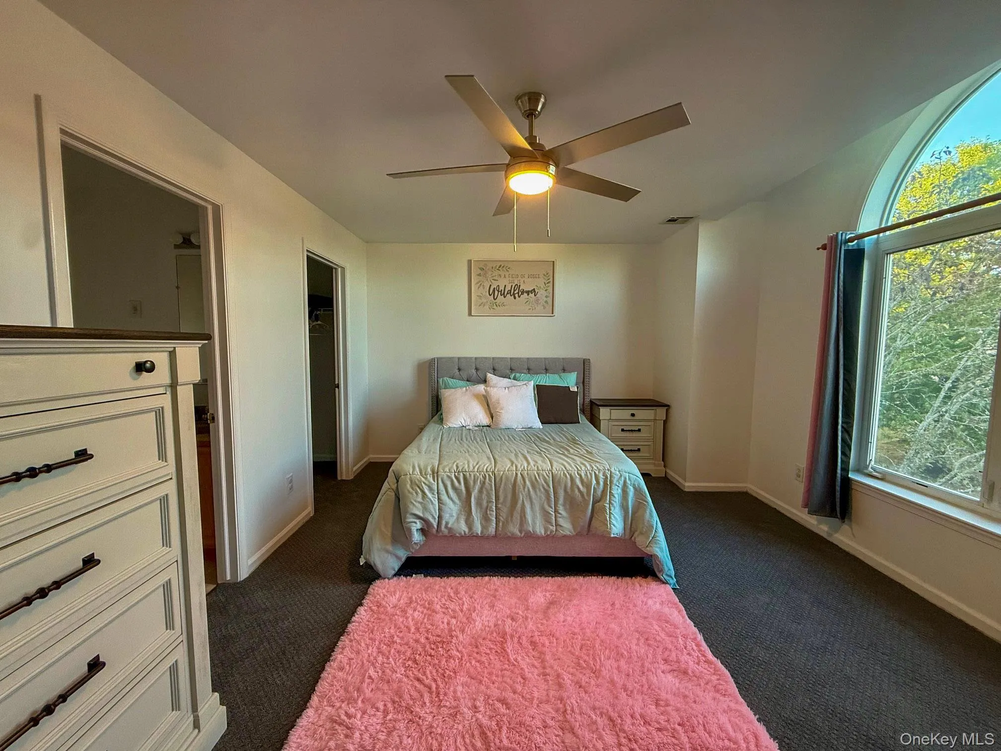 Bedroom featuring carpet flooring, a walk in closet, and a ceiling fan Bedroom featuring carpet flooring, a walk in closet, and a ceiling fan