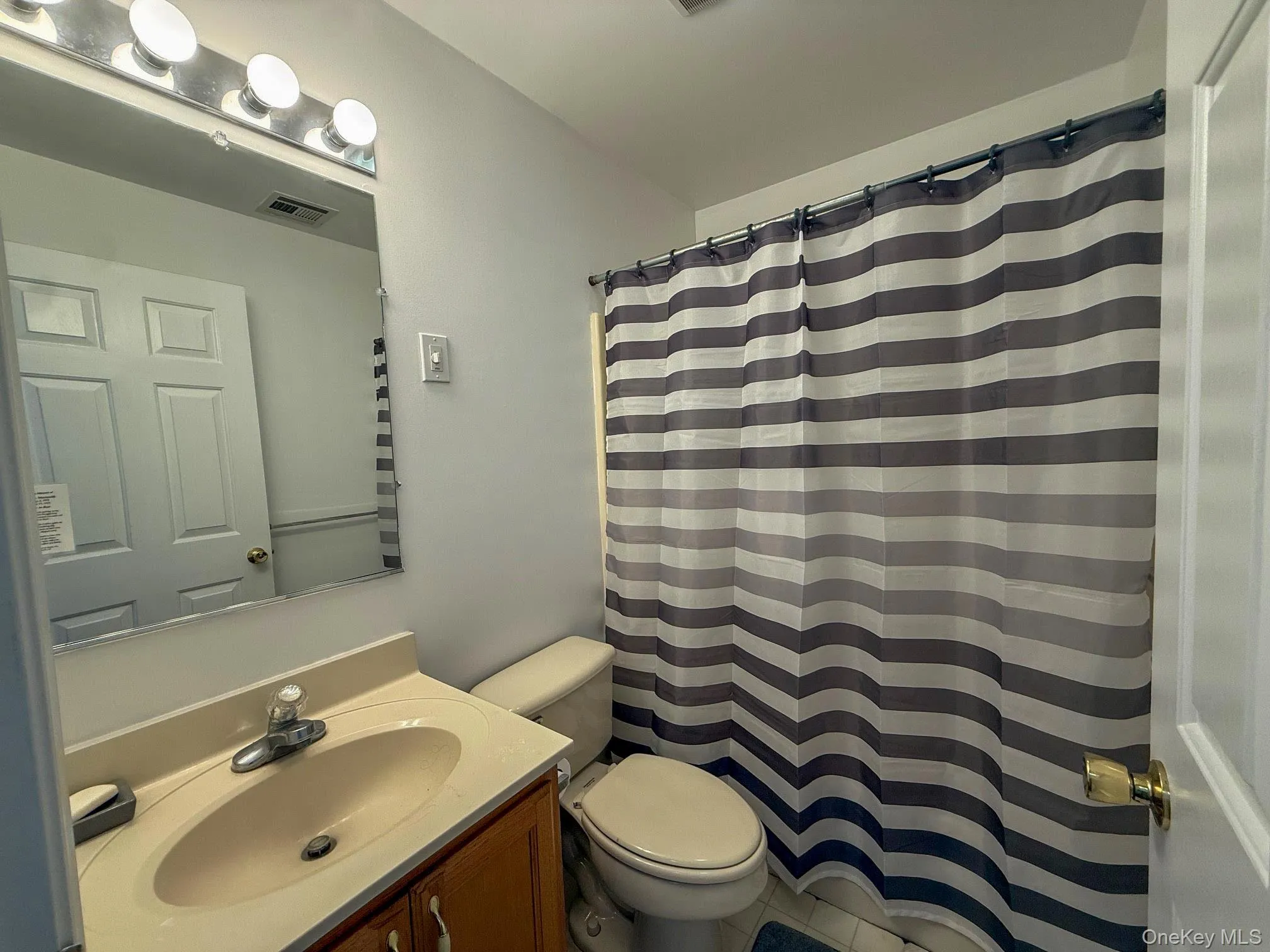 Bathroom featuring vanity, curtained shower, and tile patterned flooring Bathroom featuring vanity, curtained shower, and tile patterned flooring
