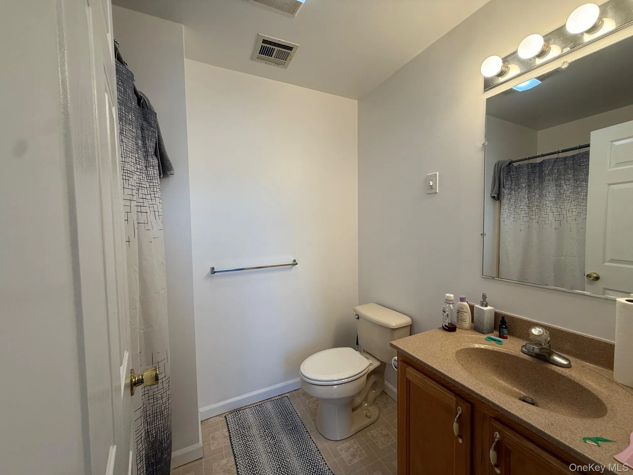 Bathroom featuring vanity, light tile patterned flooring, and a shower with curtain Bathroom featuring vanity, light tile patterned flooring, and a shower with curtain