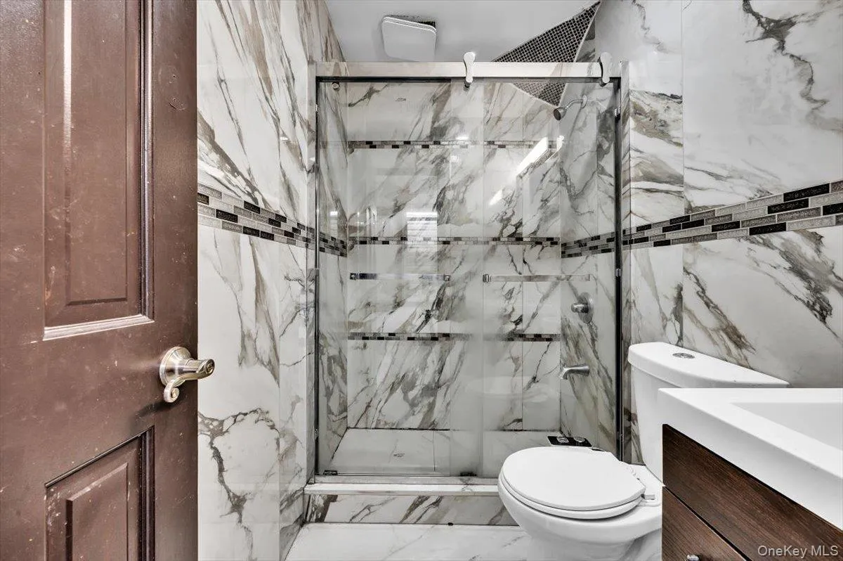 Full bath with vanity, a marble finish shower, tile walls, and marble finish floors Full bath with vanity, a marble finish shower, tile walls, and marble finish floors