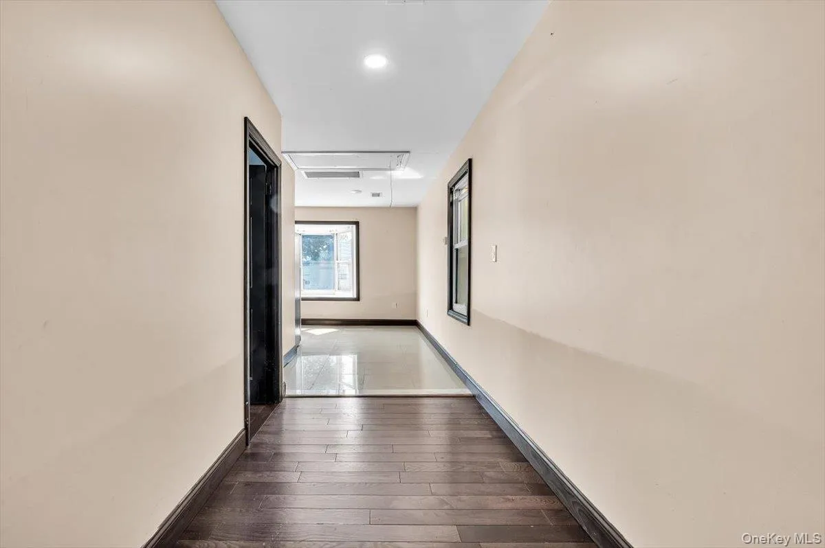 Hall featuring attic access and dark wood-style flooring Hall featuring attic access and dark wood-style flooring