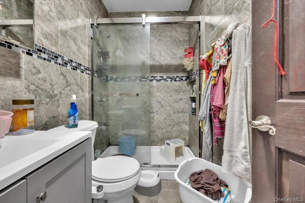 Full bathroom featuring tile walls, vanity, and a shower stall Full bathroom featuring tile walls, vanity, and a shower stall