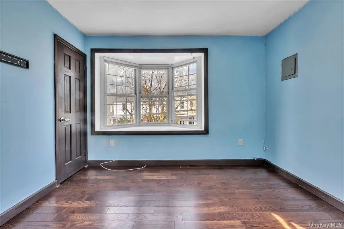 Empty room featuring dark wood finished floors and electric panel Empty room featuring dark wood finished floors and electric panel