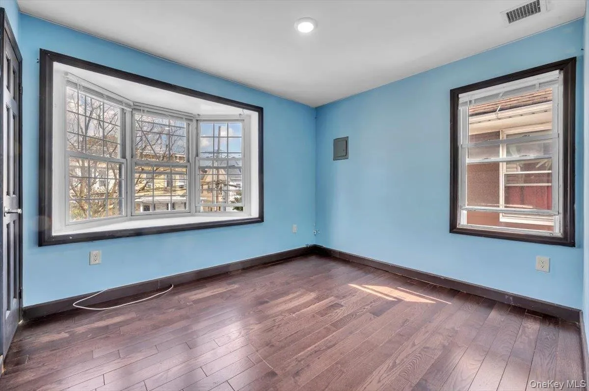 Unfurnished room with dark wood-style floors and plenty of natural light Unfurnished room with dark wood-style floors and plenty of natural light
