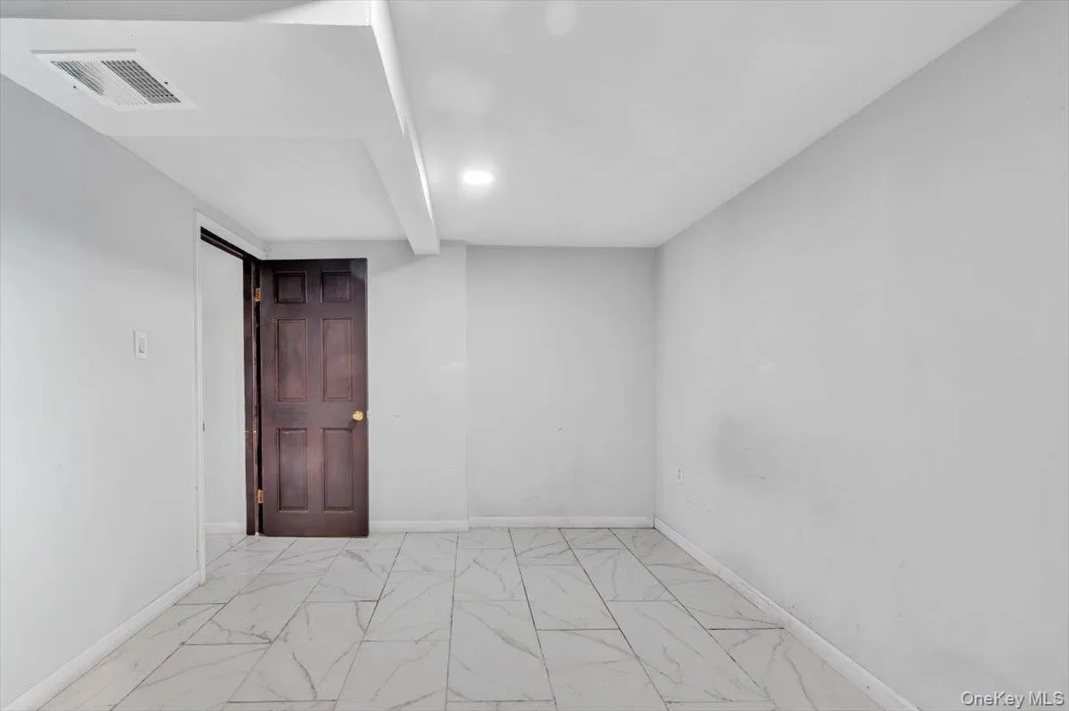 Empty room with marble look tile flooring and baseboards Empty room with marble look tile flooring and baseboards