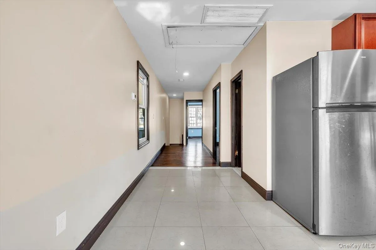 Hallway with light tile patterned floors, attic access, and recessed lighting Hallway with light tile patterned floors, attic access, and recessed lighting