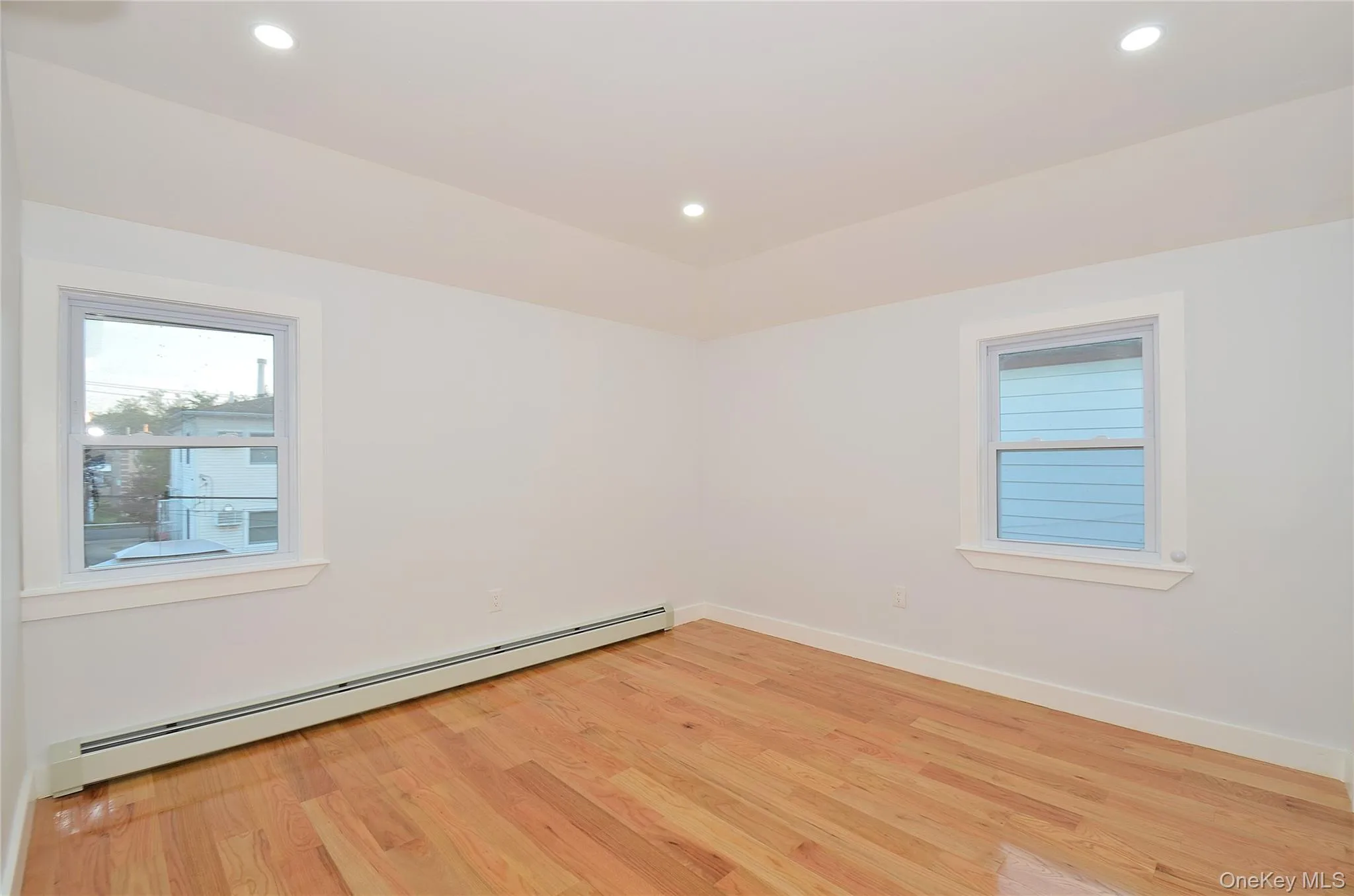 Bedroom with a baseboard radiator, light wood-type flooring, recessed lighting, and healthy amount of natural light Bedroom with a baseboard radiator, light wood-type flooring, recessed lighting, and healthy amount of natural light