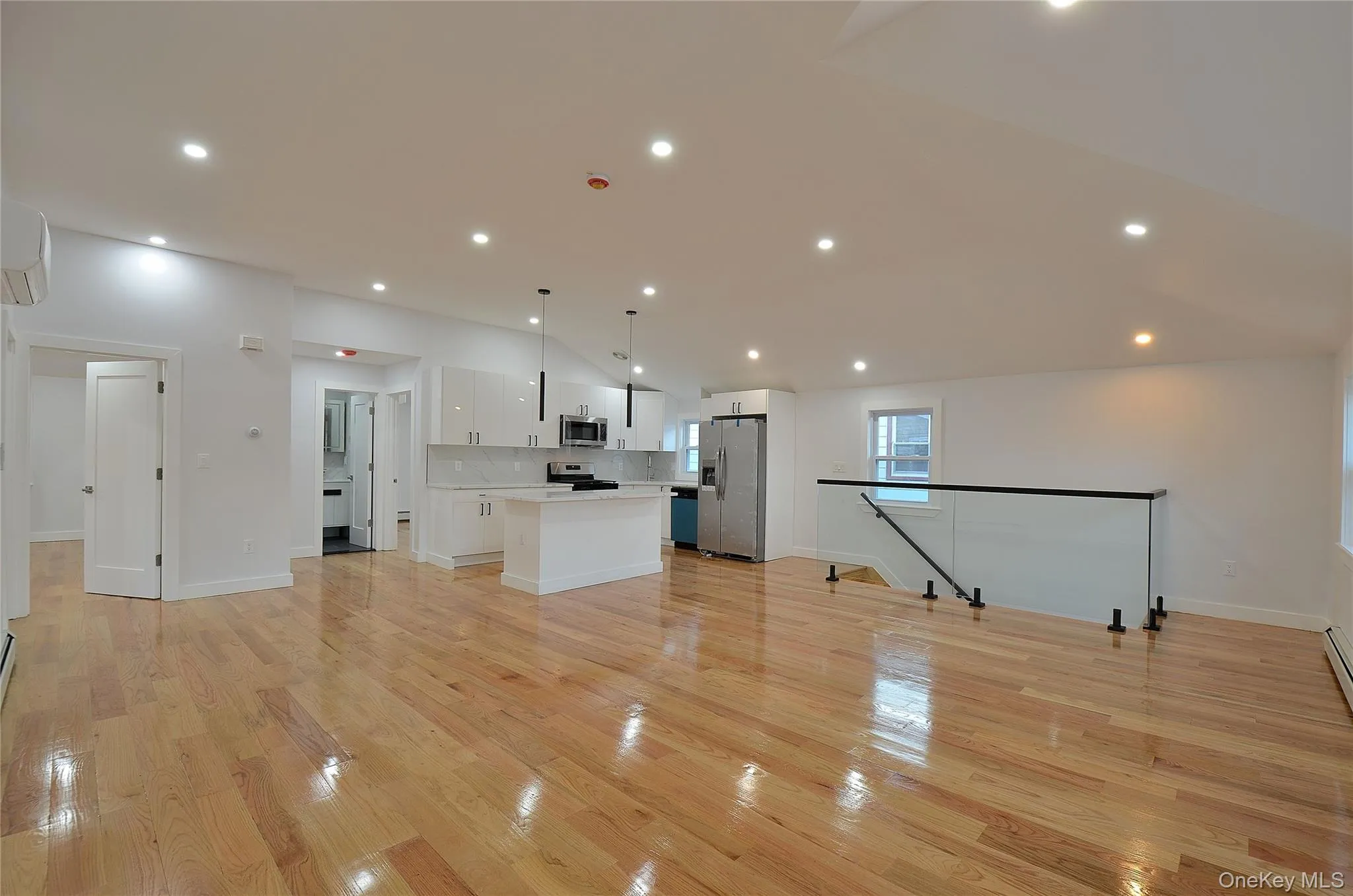 Living room with open floor plan, a kitchen island, hanging light fixtures, white cabinets, and light countertops Living room with open floor plan, a kitchen island, hanging light fixtures, white cabinets, and light countertops