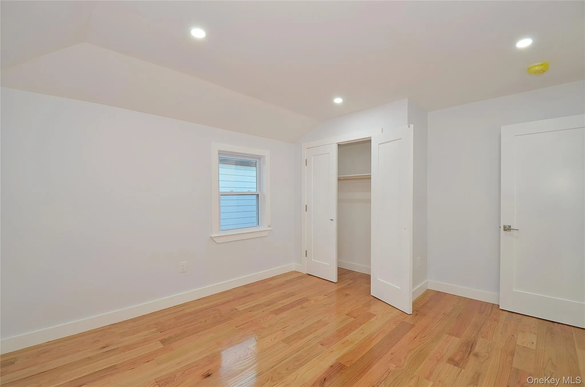 Bedroom featuring light wood-style flooring, vaulted ceiling, recessed lighting, and a closet Bedroom featuring light wood-style flooring, vaulted ceiling, recessed lighting, and a closet