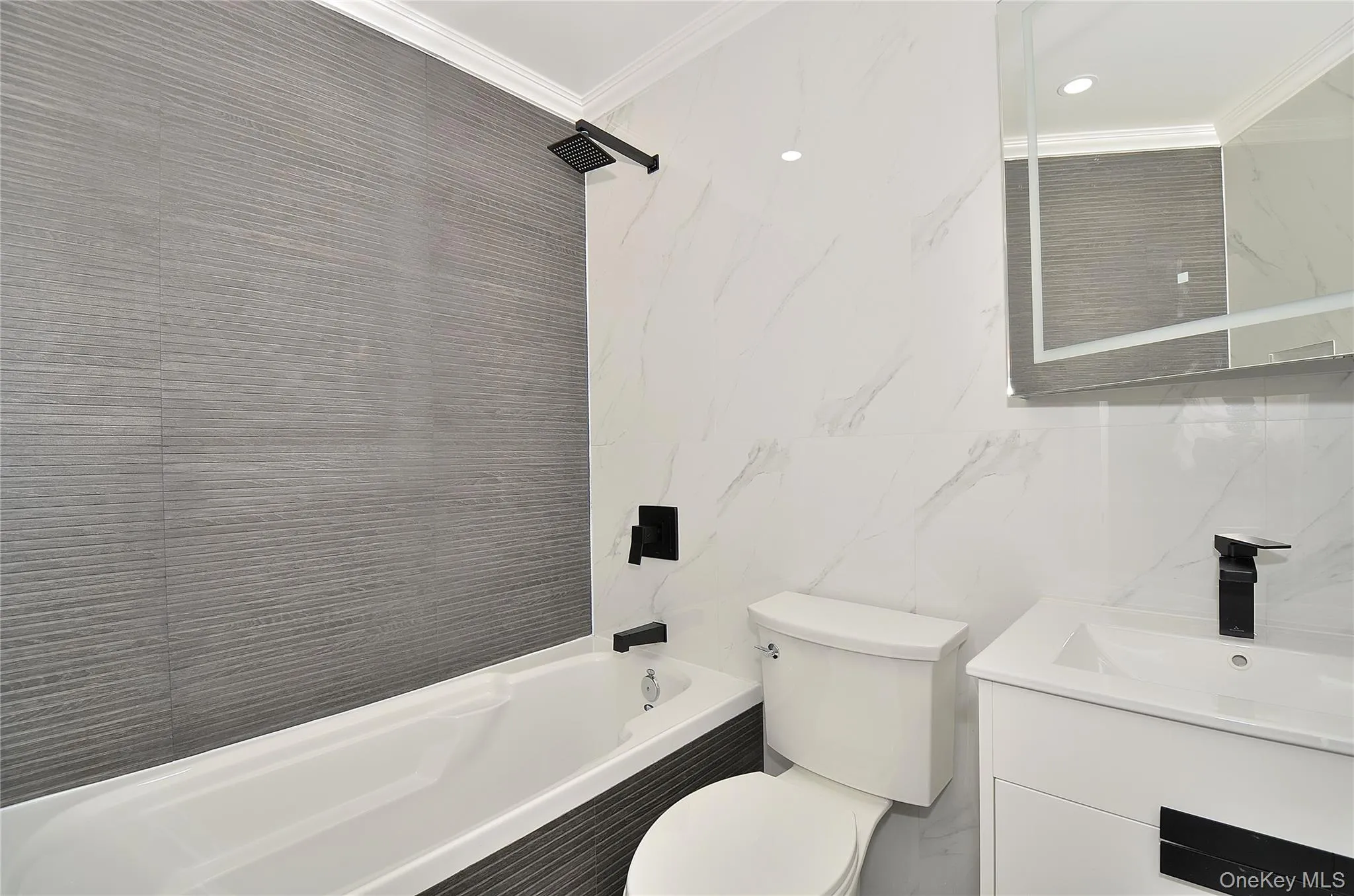 Bathroom featuring crown molding, tile walls, vanity, shower / bath combination, and recessed lighting Bathroom featuring crown molding, tile walls, vanity, shower / bath combination, and recessed lighting