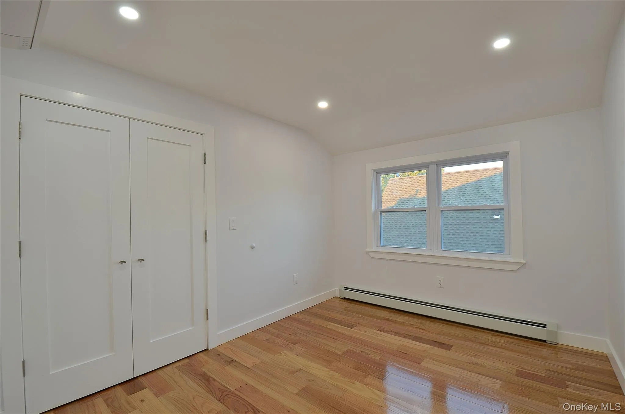 Bedroom with a baseboard radiator, recessed lighting, light wood-type flooring, a closet, and lofted ceiling Bedroom with a baseboard radiator, recessed lighting, light wood-type flooring, a closet, and lofted ceiling
