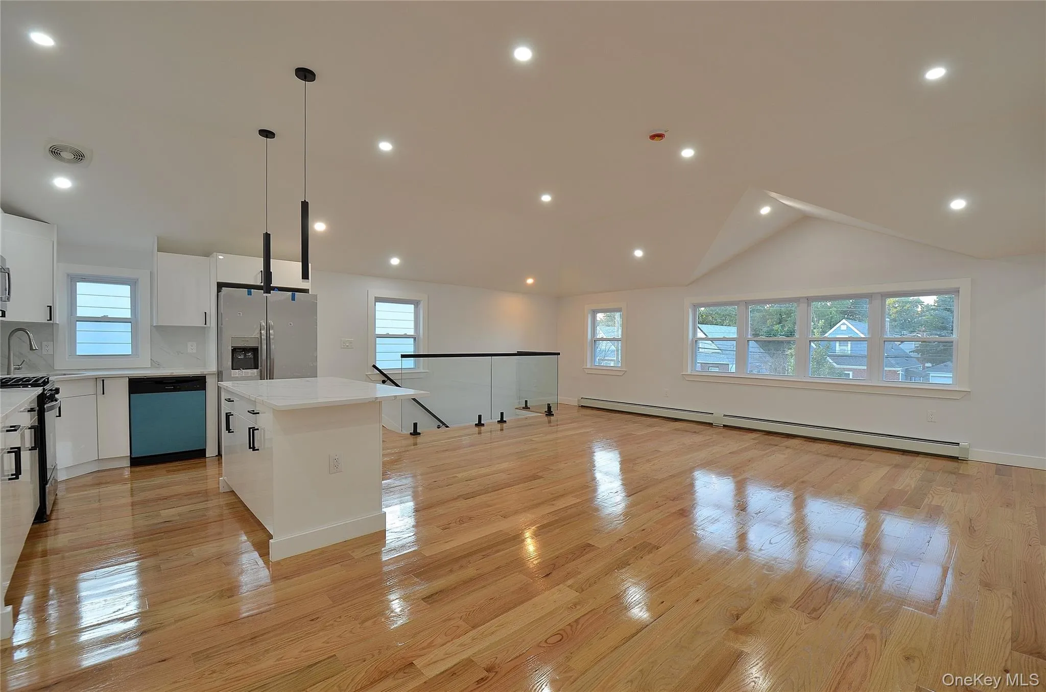 Living room featuring plenty of natural light, a baseboard heating unit, light wood-type flooring, lofted ceiling, and recessed lighting Living room featuring plenty of natural light, a baseboard heating unit, light wood-type flooring, lofted ceiling, and recessed lighting