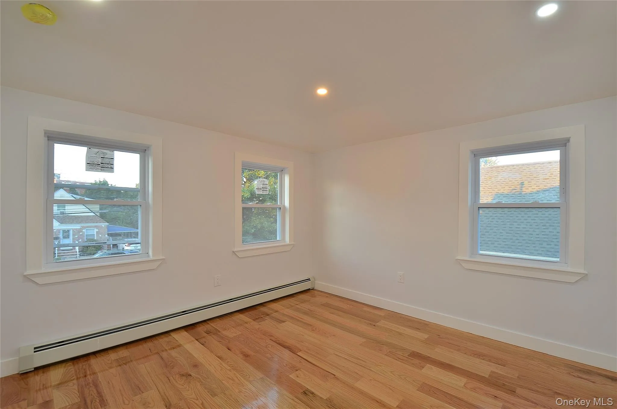 Bedroom featuring a baseboard radiator, plenty of natural light, recessed lighting, and light wood-style flooring Bedroom featuring a baseboard radiator, plenty of natural light, recessed lighting, and light wood-style flooring