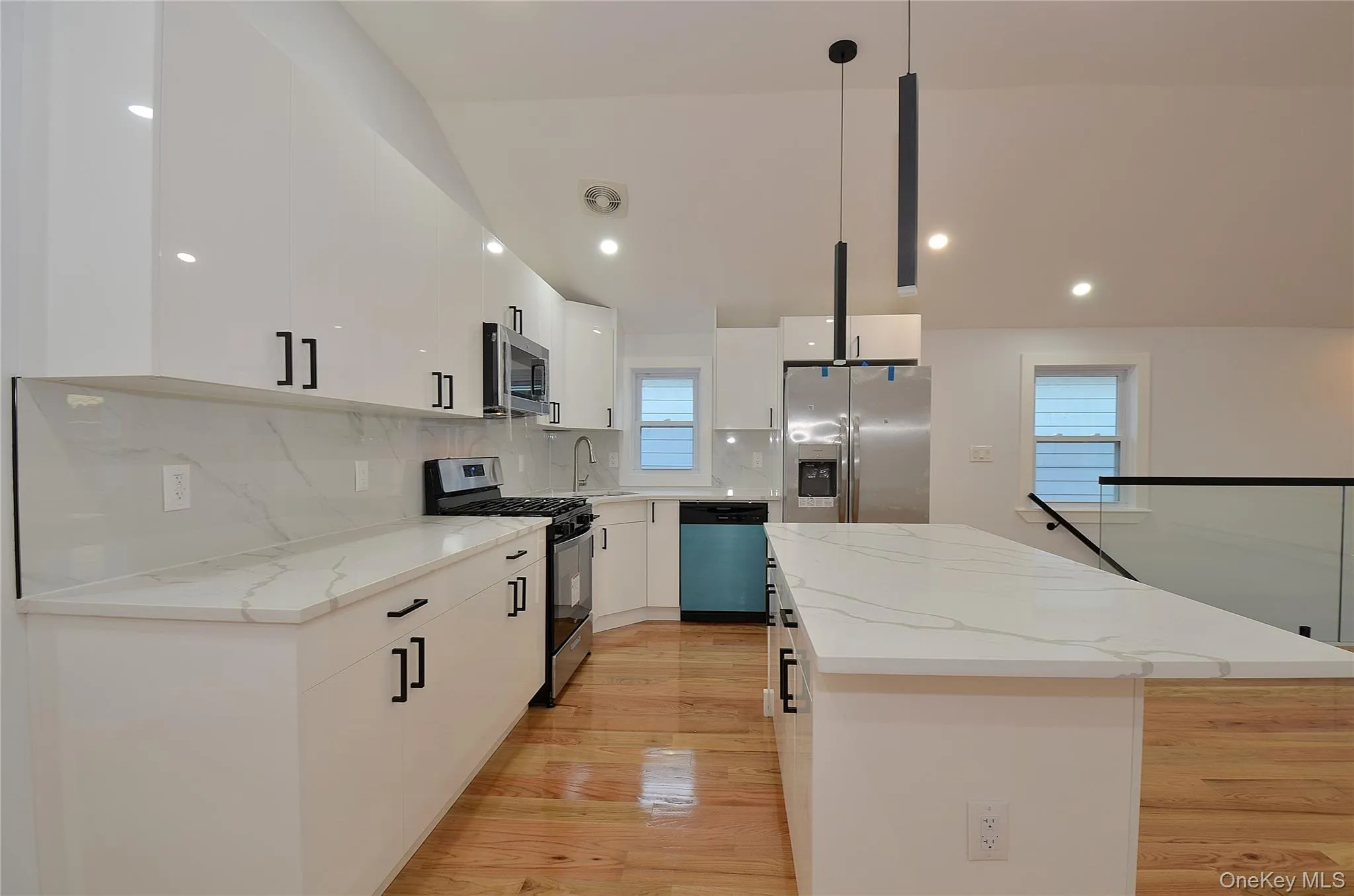 Kitchen featuring stainless steel appliances, backsplash, a kitchen island, pendant lighting, and light stone countertops Kitchen featuring stainless steel appliances, backsplash, a kitchen island, pendant lighting, and light stone countertops