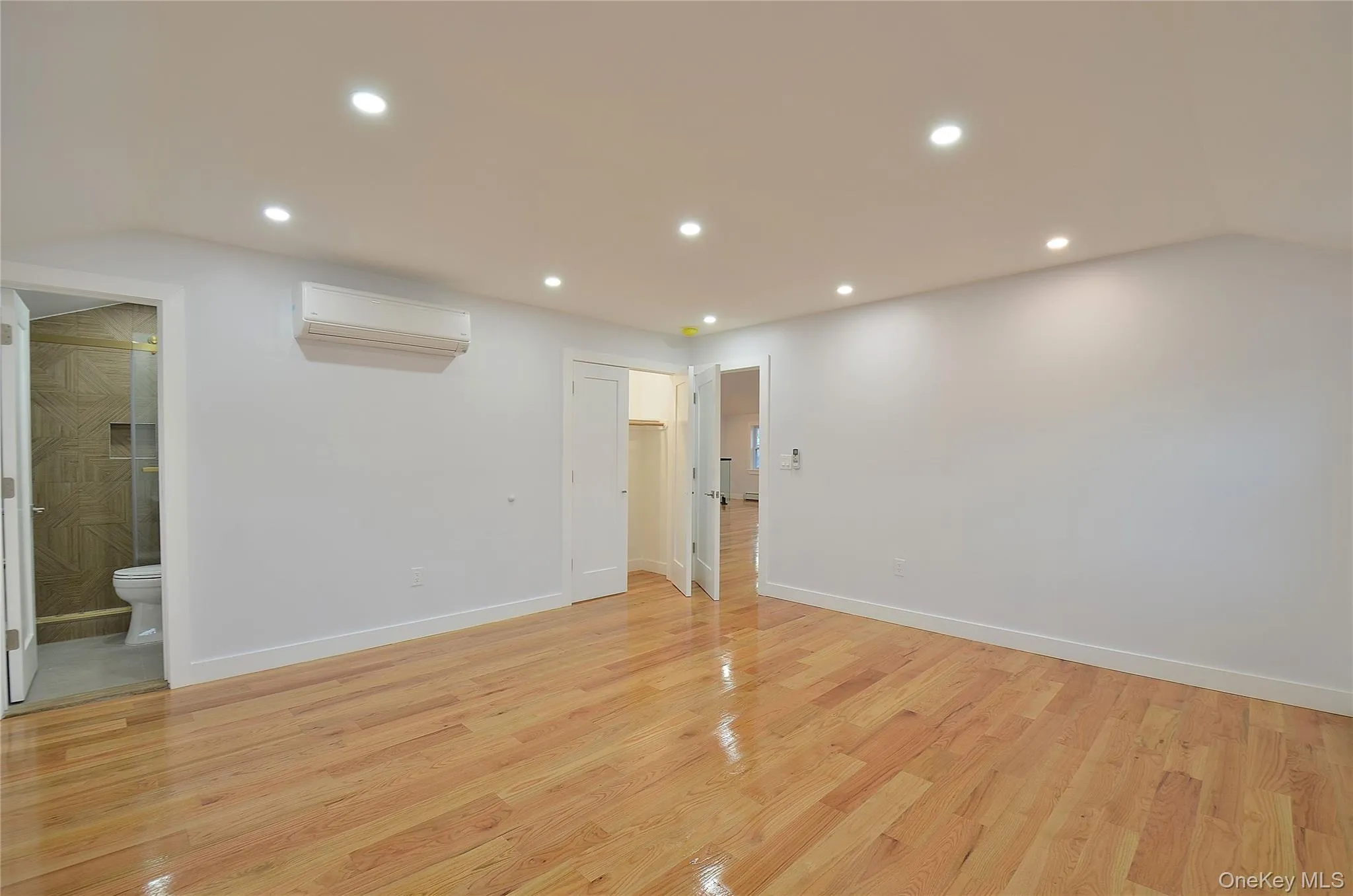 Bedroom with light wood-style flooring, recessed lighting, and a wall mounted air conditioner Bedroom with light wood-style flooring, recessed lighting, and a wall mounted air conditioner