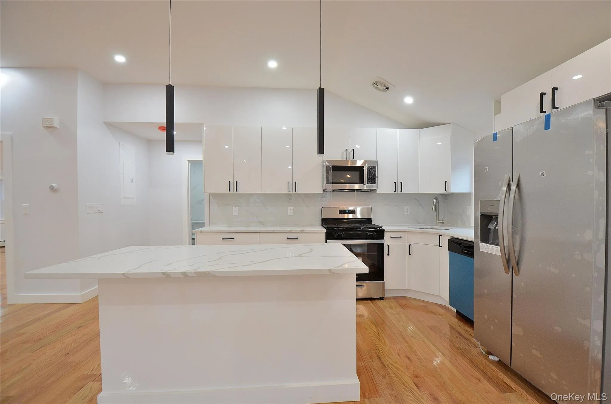 Kitchen featuring backsplash, appliances with stainless steel finishes, hanging light fixtures, light stone counters, and white cabinets Kitchen featuring backsplash, appliances with stainless steel finishes, hanging light fixtures, light stone counters, and white cabinets
