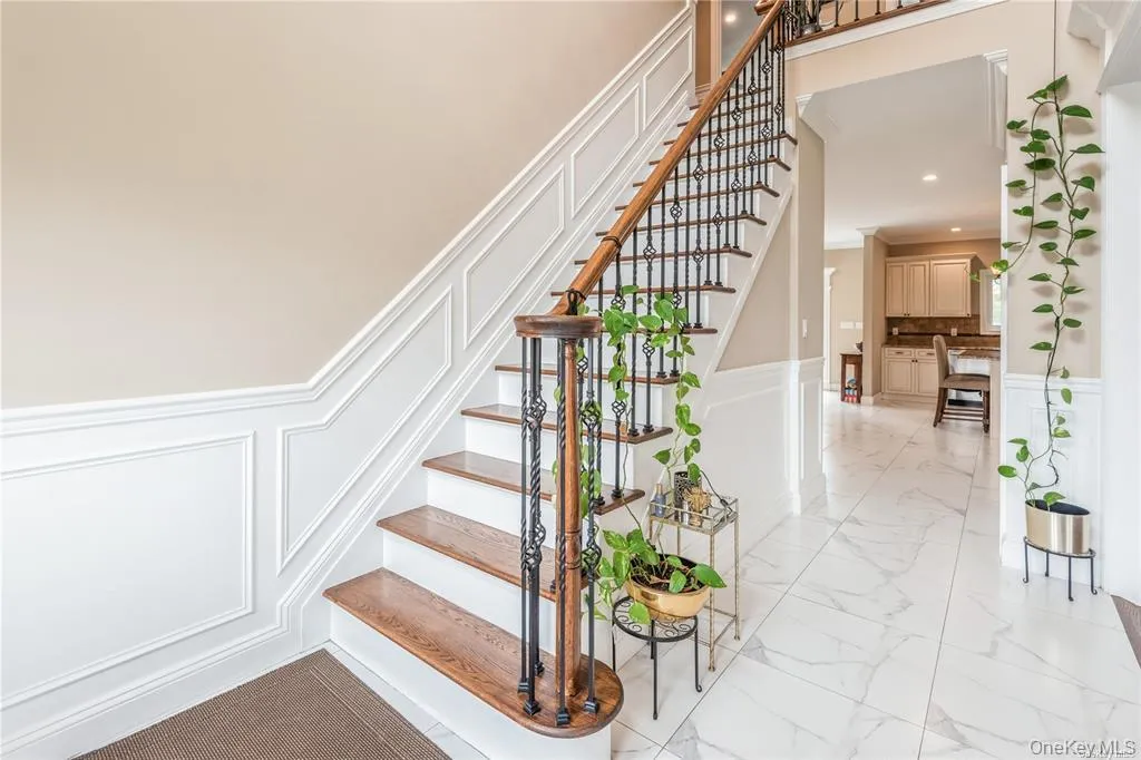 Stairway with a decorative wall, wainscoting, marble finish floors, and recessed lighting Stairway with a decorative wall, wainscoting, marble finish floors, and recessed lighting