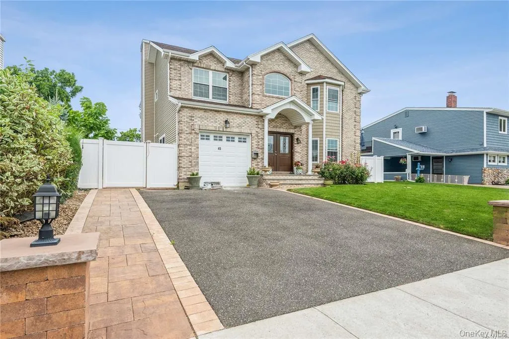 View of front of home with driveway, brick siding, an attached garage, and a gate View of front of home with driveway, brick siding, an attached garage, and a gate