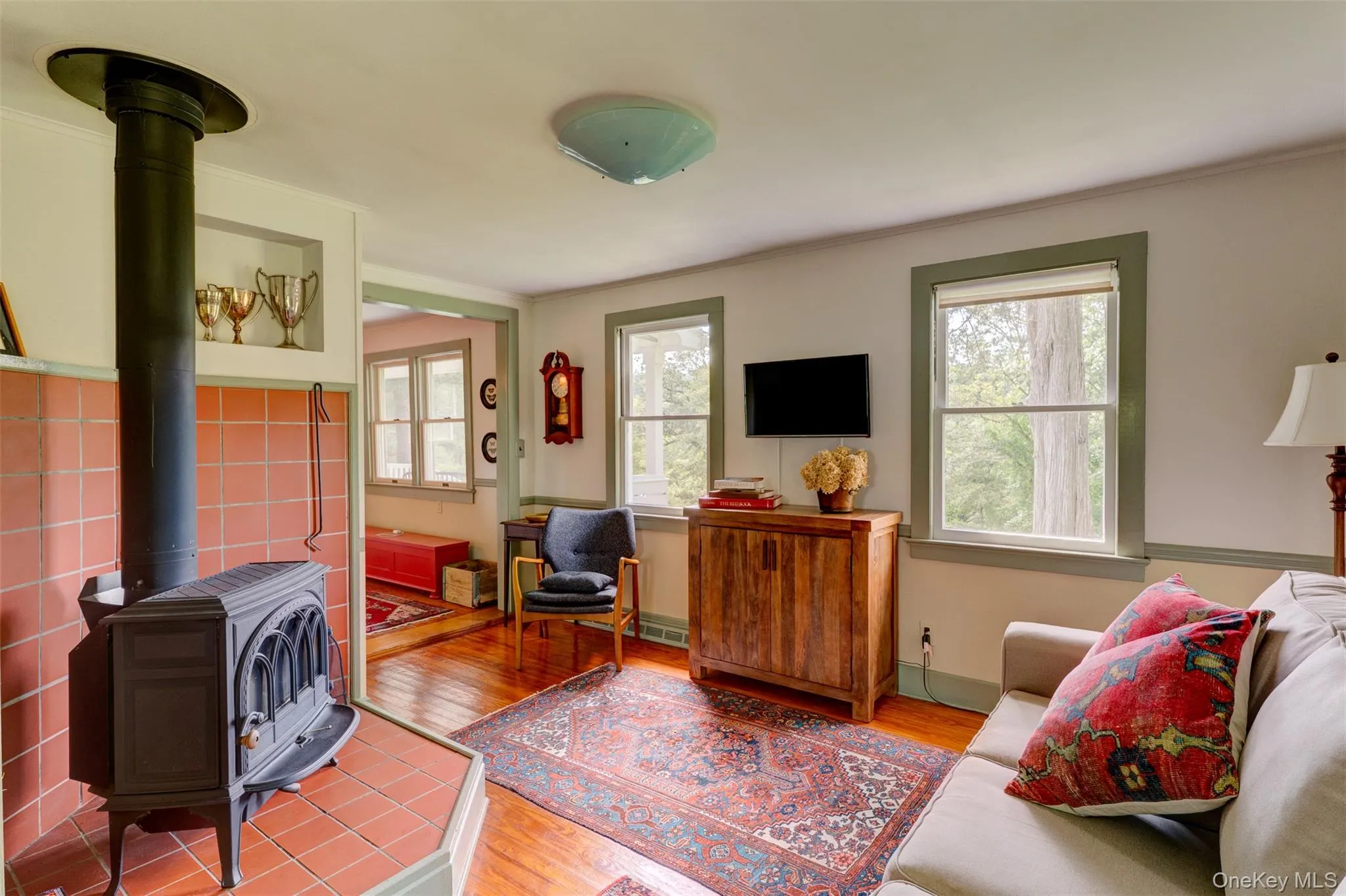 Living area featuring a wood stove, wood finished floors, and ornamental molding Living area featuring a wood stove, wood finished floors, and ornamental molding