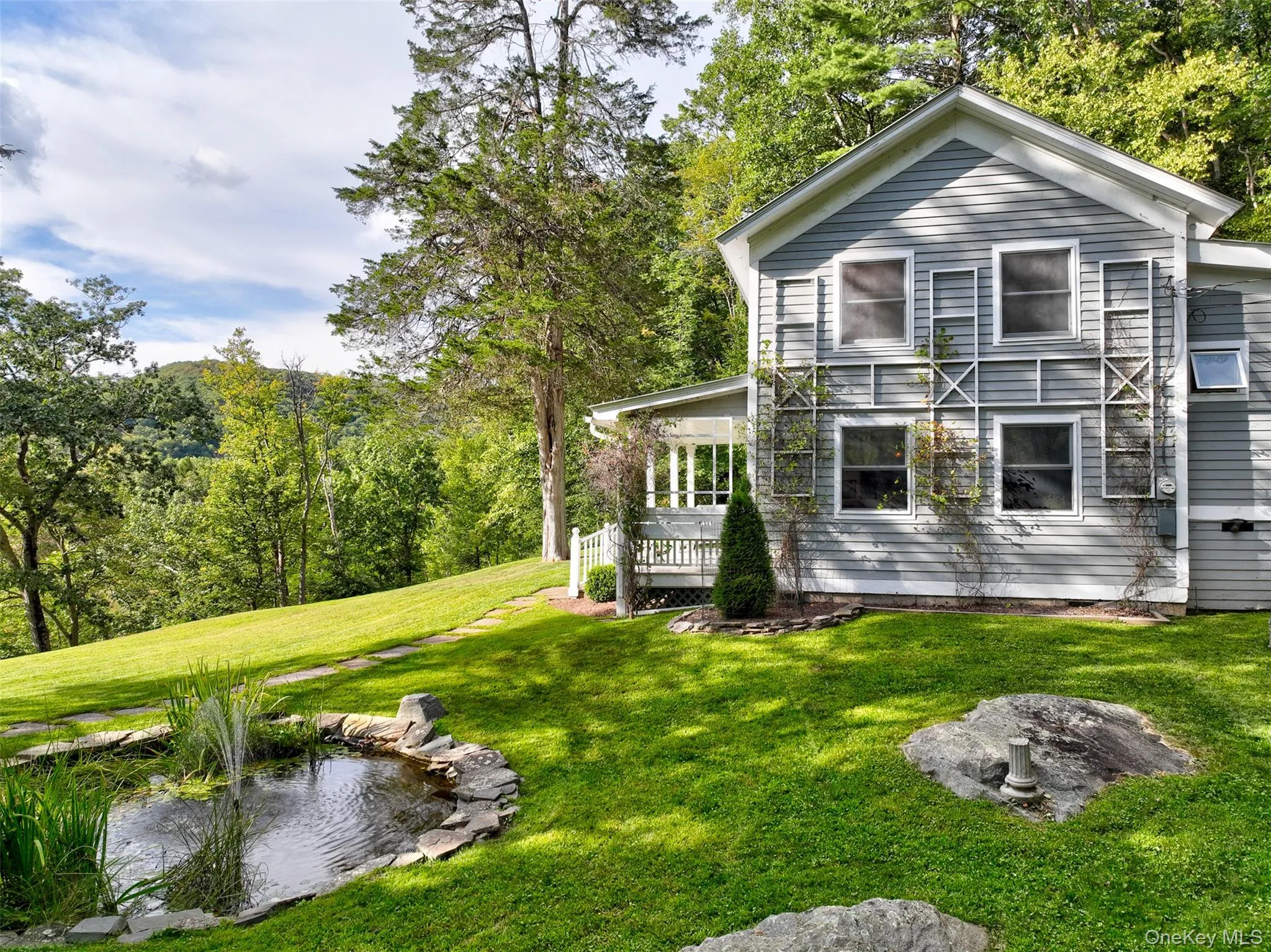 View of home's exterior with a lawn and a small pond View of home's exterior with a lawn and a small pond