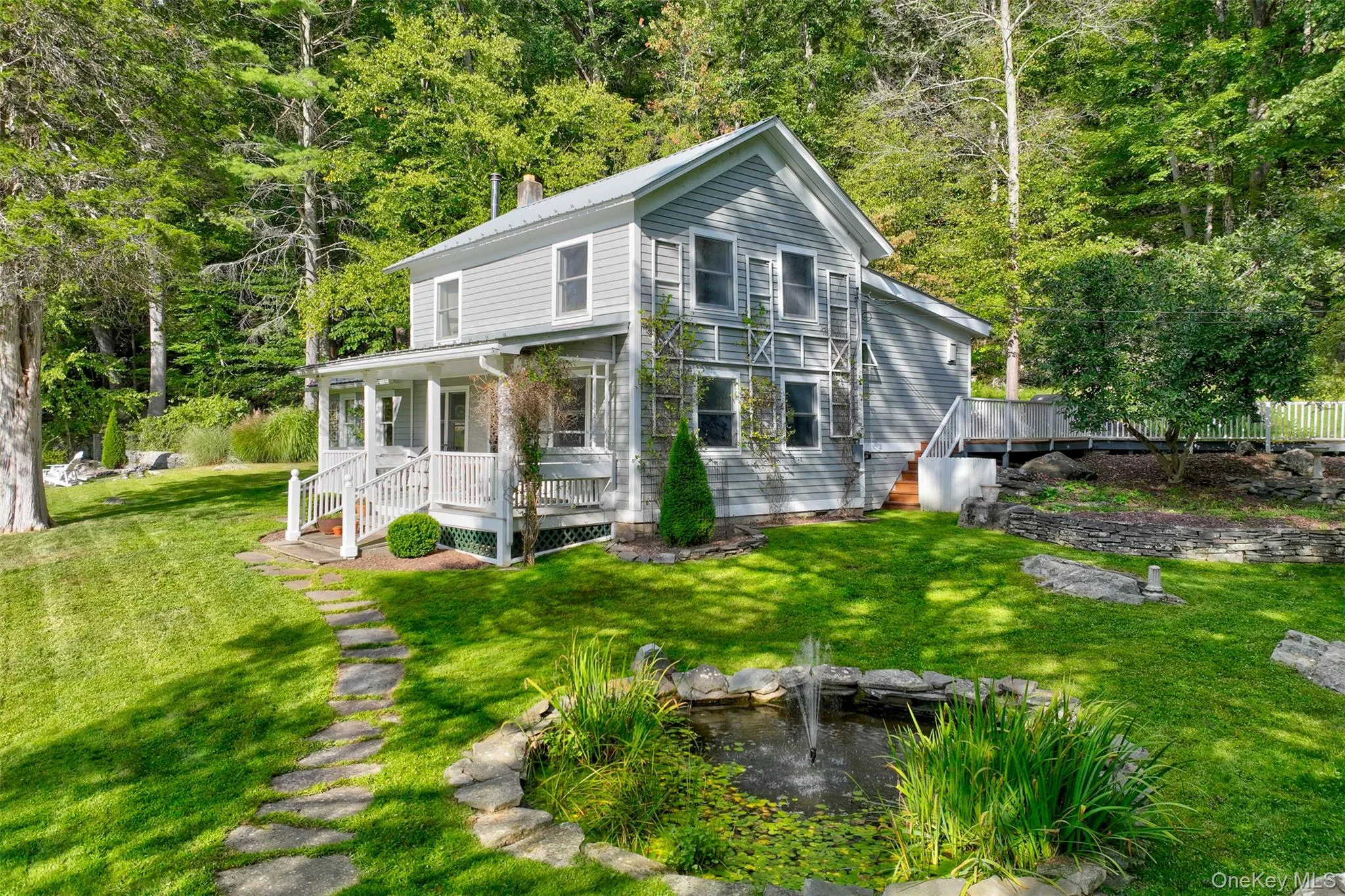 View of front facade with a front lawn, a chimney, a porch, and a garden pond View of front facade with a front lawn, a chimney, a porch, and a garden pond
