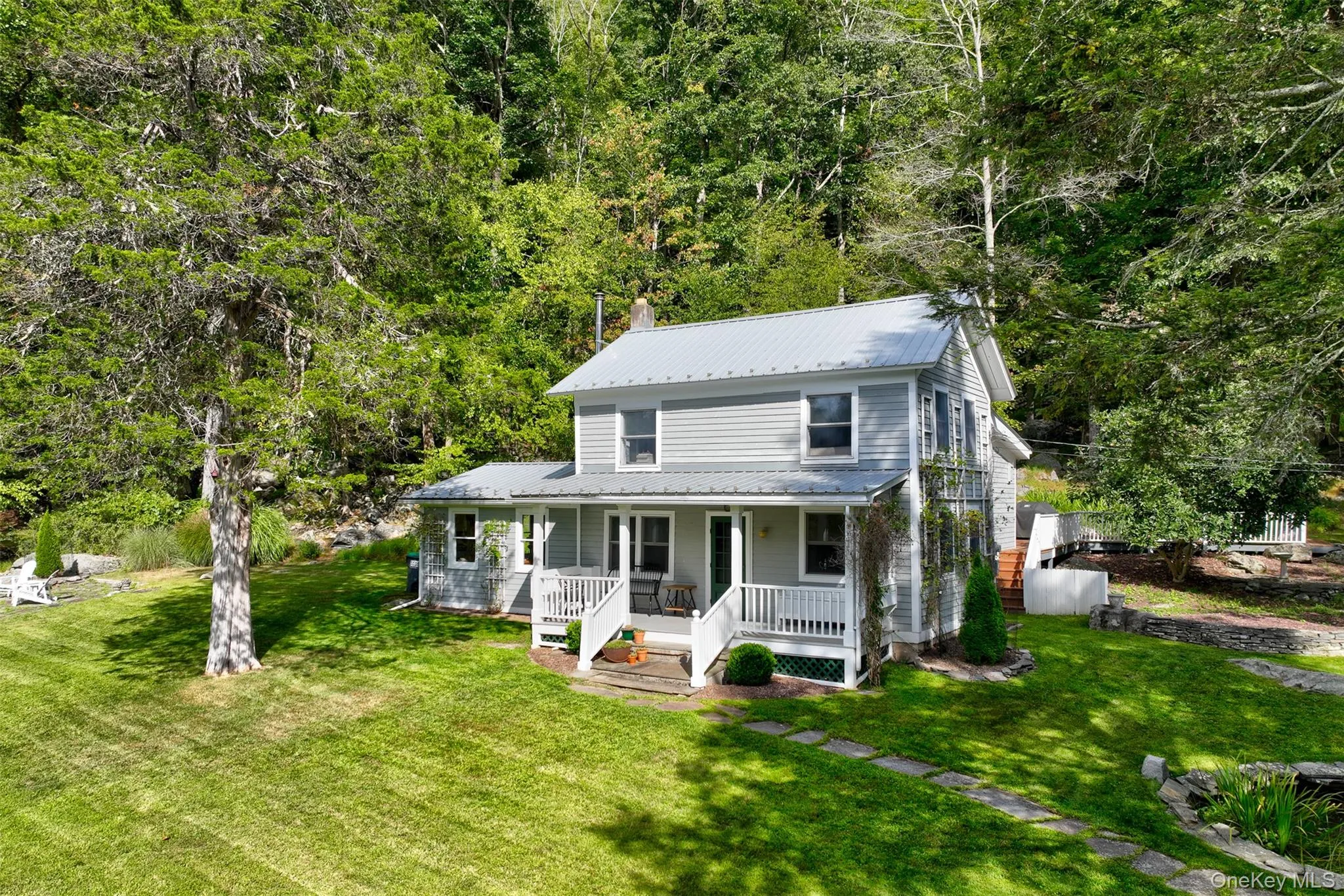 View of front of house with a porch, a metal roof, a front lawn, and a chimney View of front of house with a porch, a metal roof, a front lawn, and a chimney
