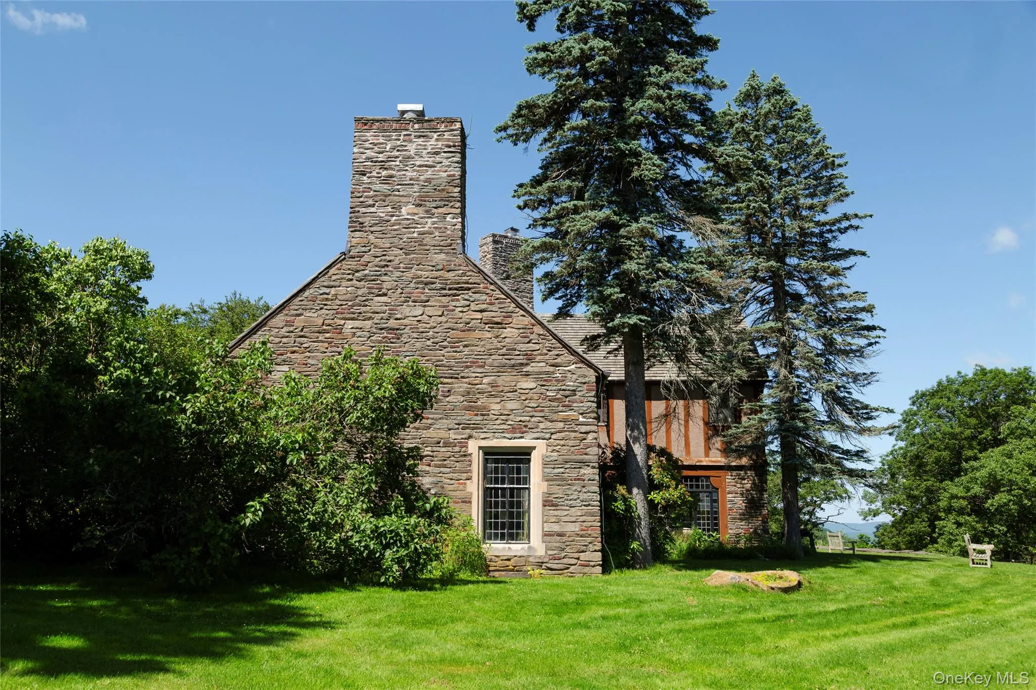 View of home's exterior featuring a chimney, a yard, and stone siding View of home's exterior featuring a chimney, a yard, and stone siding