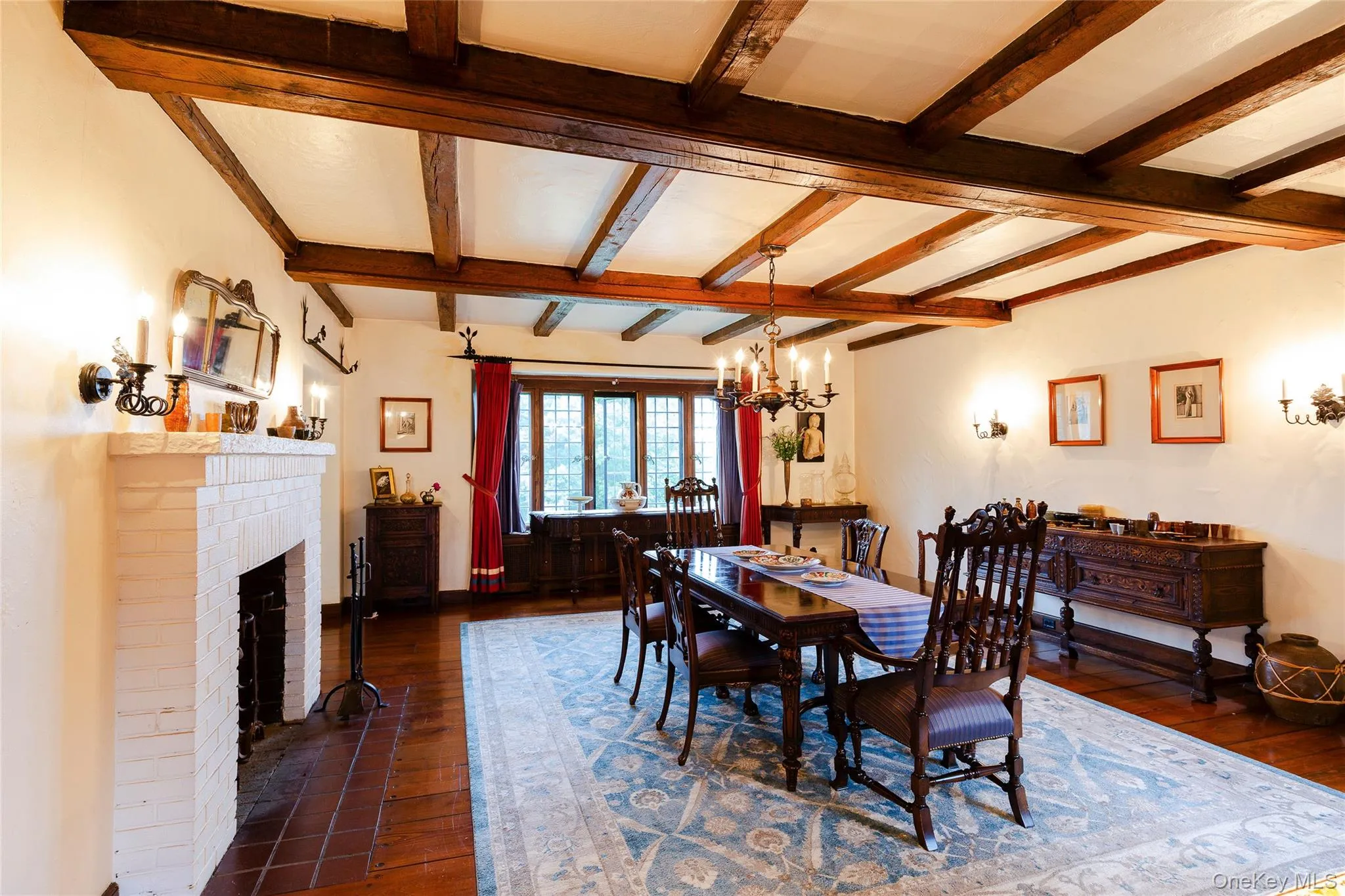 Dining area with a fireplace, dark wood finished floors, beamed ceiling, and a chandelier Dining area with a fireplace, dark wood finished floors, beamed ceiling, and a chandelier