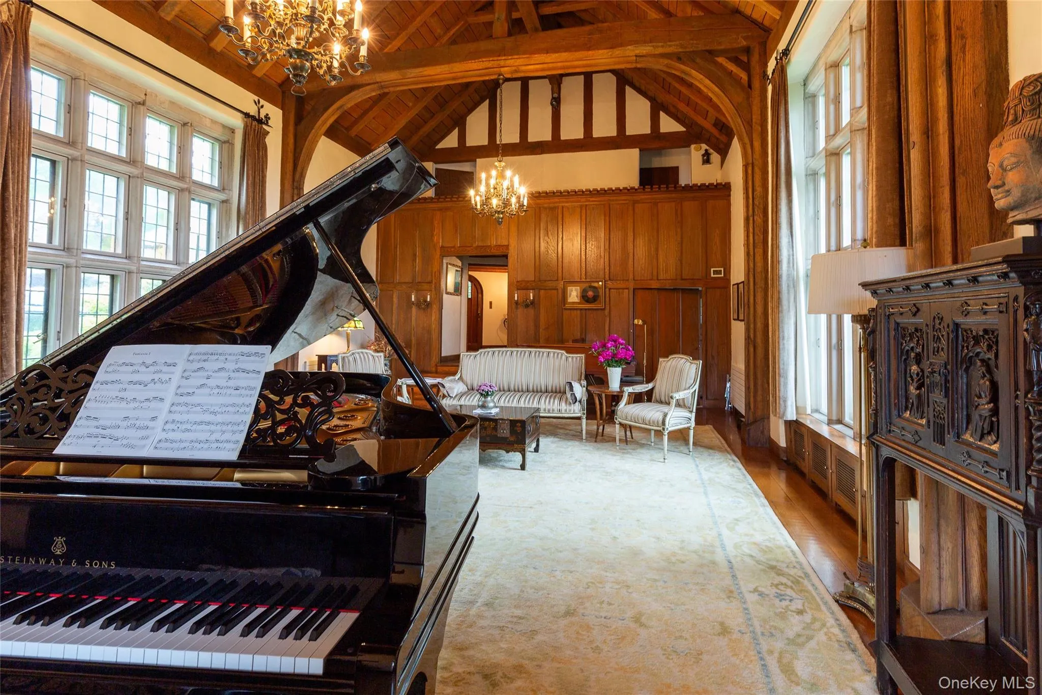 Sitting room featuring a chandelier, light wood-type flooring, high vaulted ceiling, wood walls, and a wood ceiling with exposed beams Sitting room featuring a chandelier, light wood-type flooring, high vaulted ceiling, wood walls, and a wood ceiling with exposed beams
