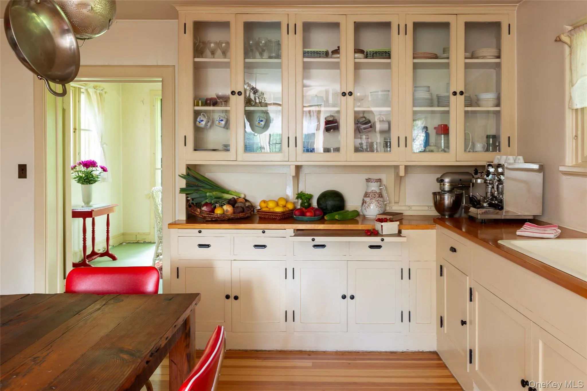 Kitchen with glass insert cabinets, light wood-style floors, white cabinets, and wood counters Kitchen with glass insert cabinets, light wood-style floors, white cabinets, and wood counters