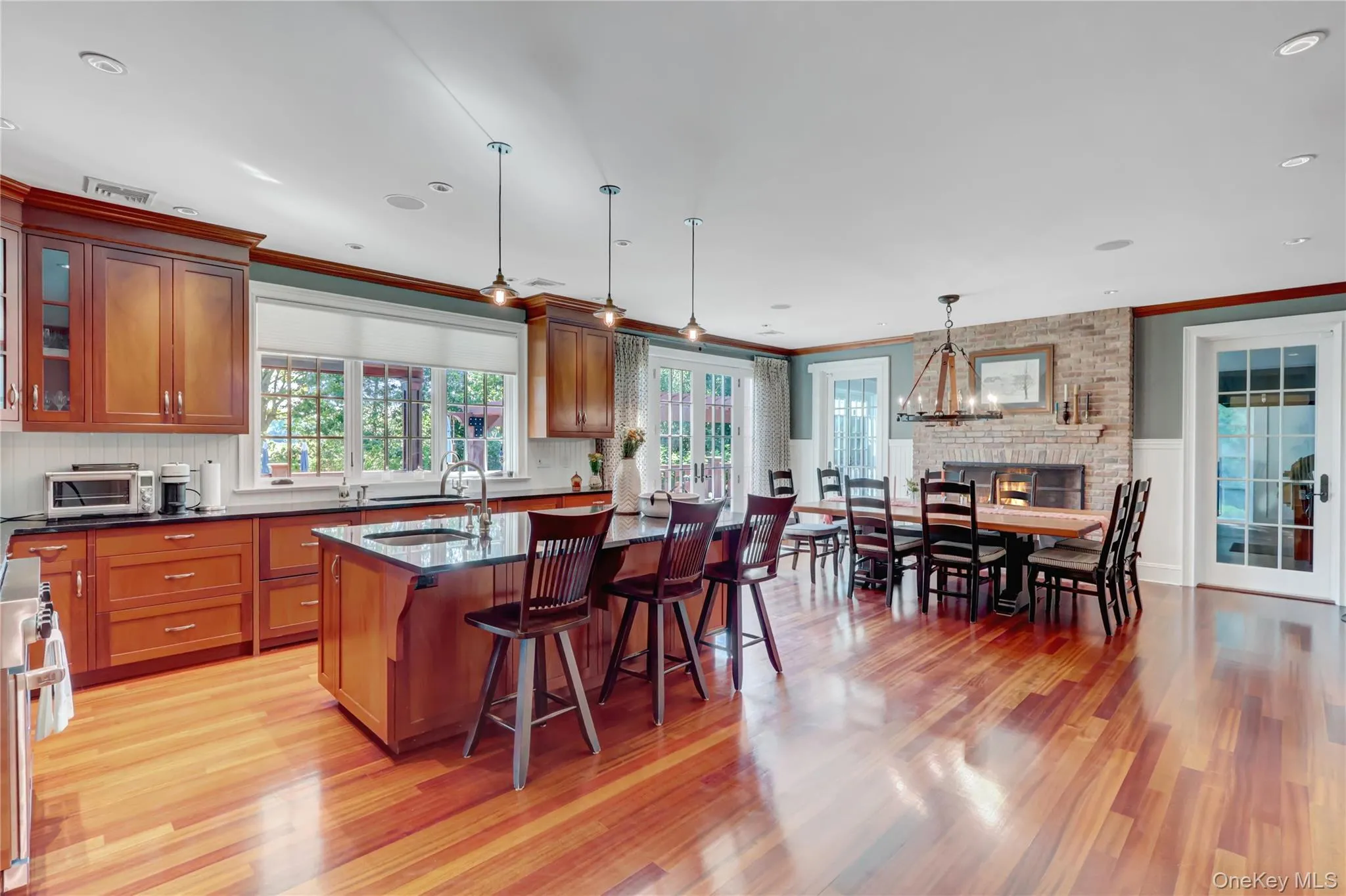 Kitchen with a kitchen breakfast bar, pendant lighting, glass insert cabinets, light wood-style flooring, and crown molding Kitchen with a kitchen breakfast bar, pendant lighting, glass insert cabinets, light wood-style flooring, and crown molding