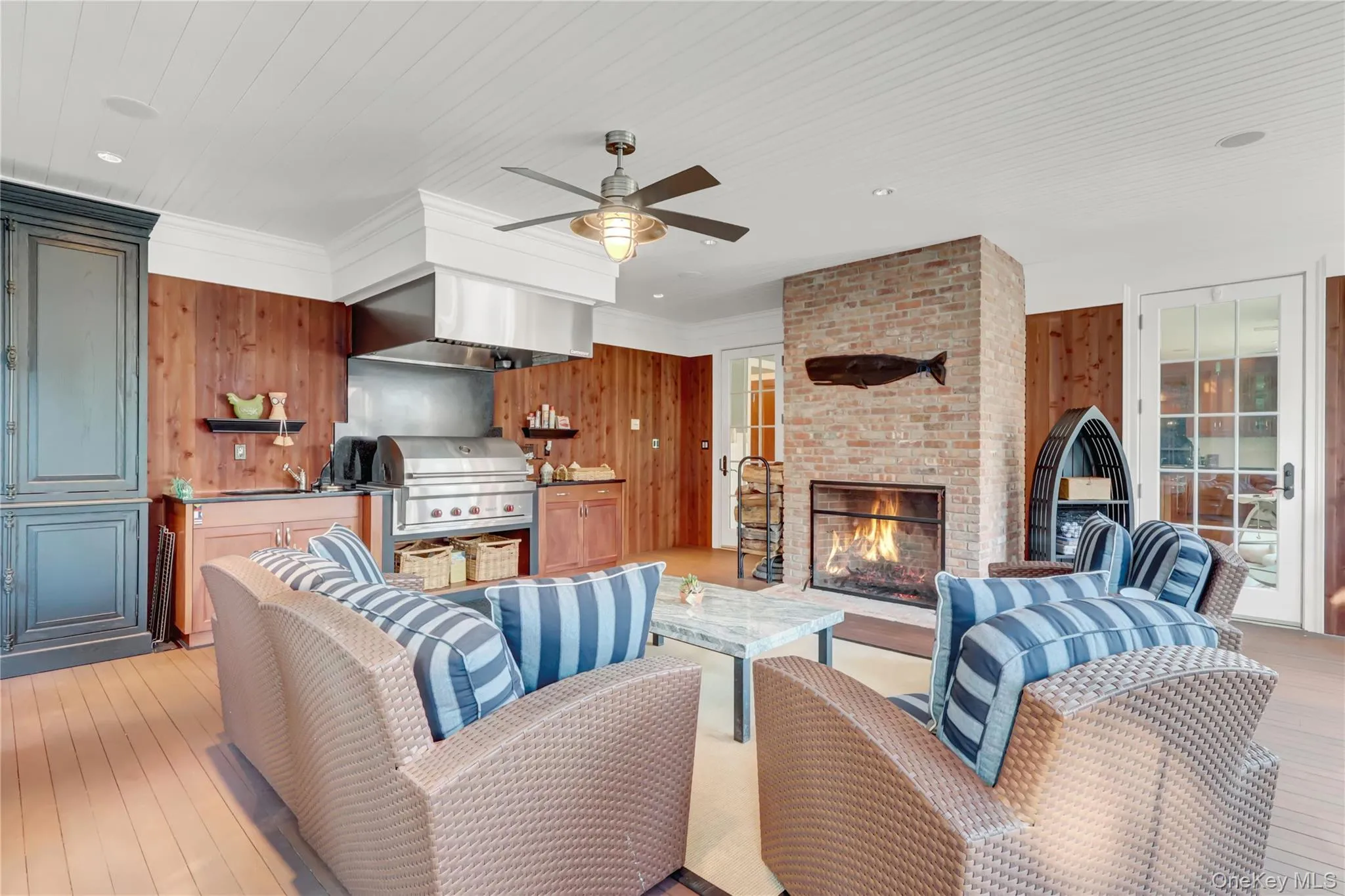Living room with wood walls, a brick fireplace, light wood-style flooring, crown molding, and a ceiling fan Living room with wood walls, a brick fireplace, light wood-style flooring, crown molding, and a ceiling fan