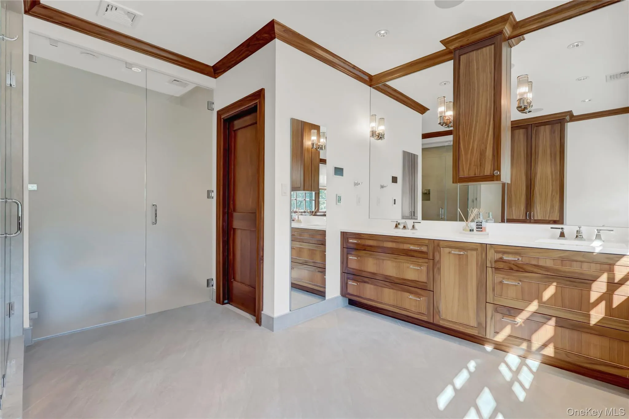 Full bathroom with ornamental molding, double vanity, a stall shower, and a chandelier Full bathroom with ornamental molding, double vanity, a stall shower, and a chandelier