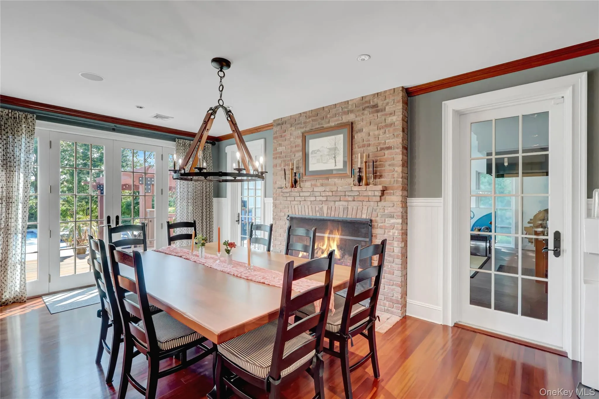 Dining room with french doors, plenty of natural light, a chandelier, a fireplace, and wainscoting Dining room with french doors, plenty of natural light, a chandelier, a fireplace, and wainscoting
