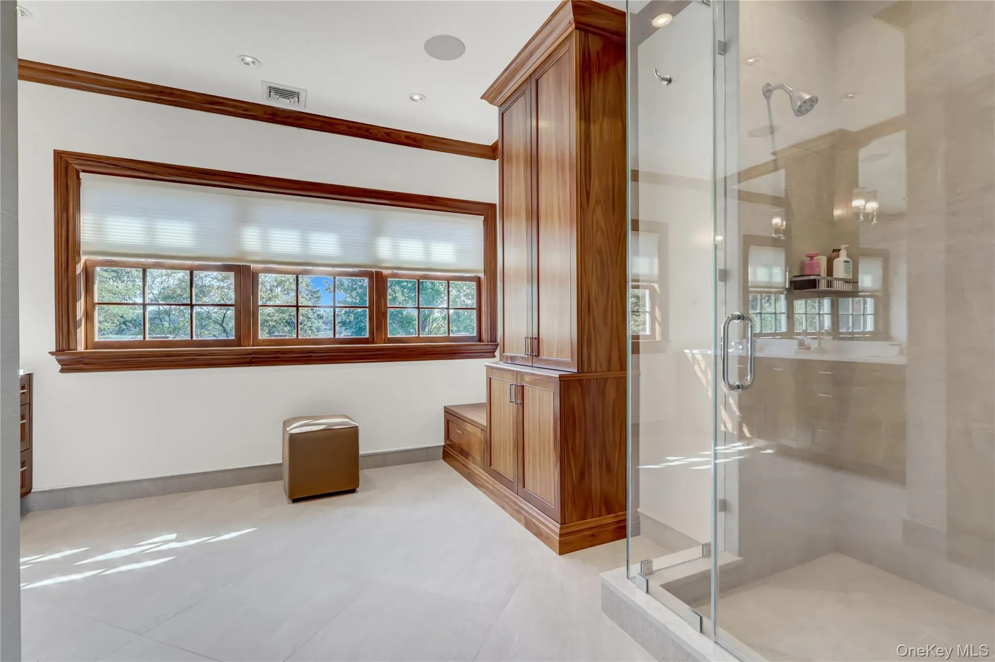 Bathroom with a stall shower, ornamental molding, and light tile patterned floors Bathroom with a stall shower, ornamental molding, and light tile patterned floors