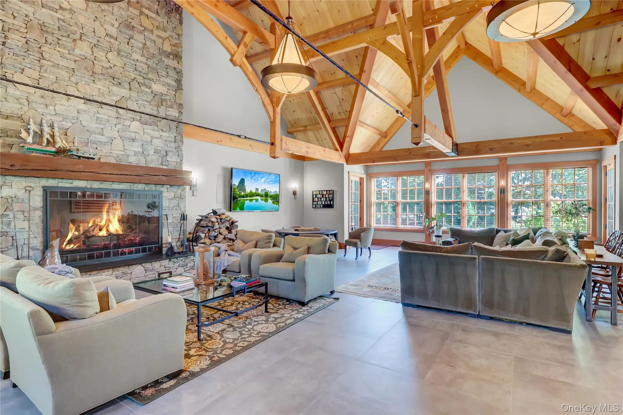 Living room with high vaulted ceiling, beamed ceiling, healthy amount of natural light, and a stone fireplace Living room with high vaulted ceiling, beamed ceiling, healthy amount of natural light, and a stone fireplace