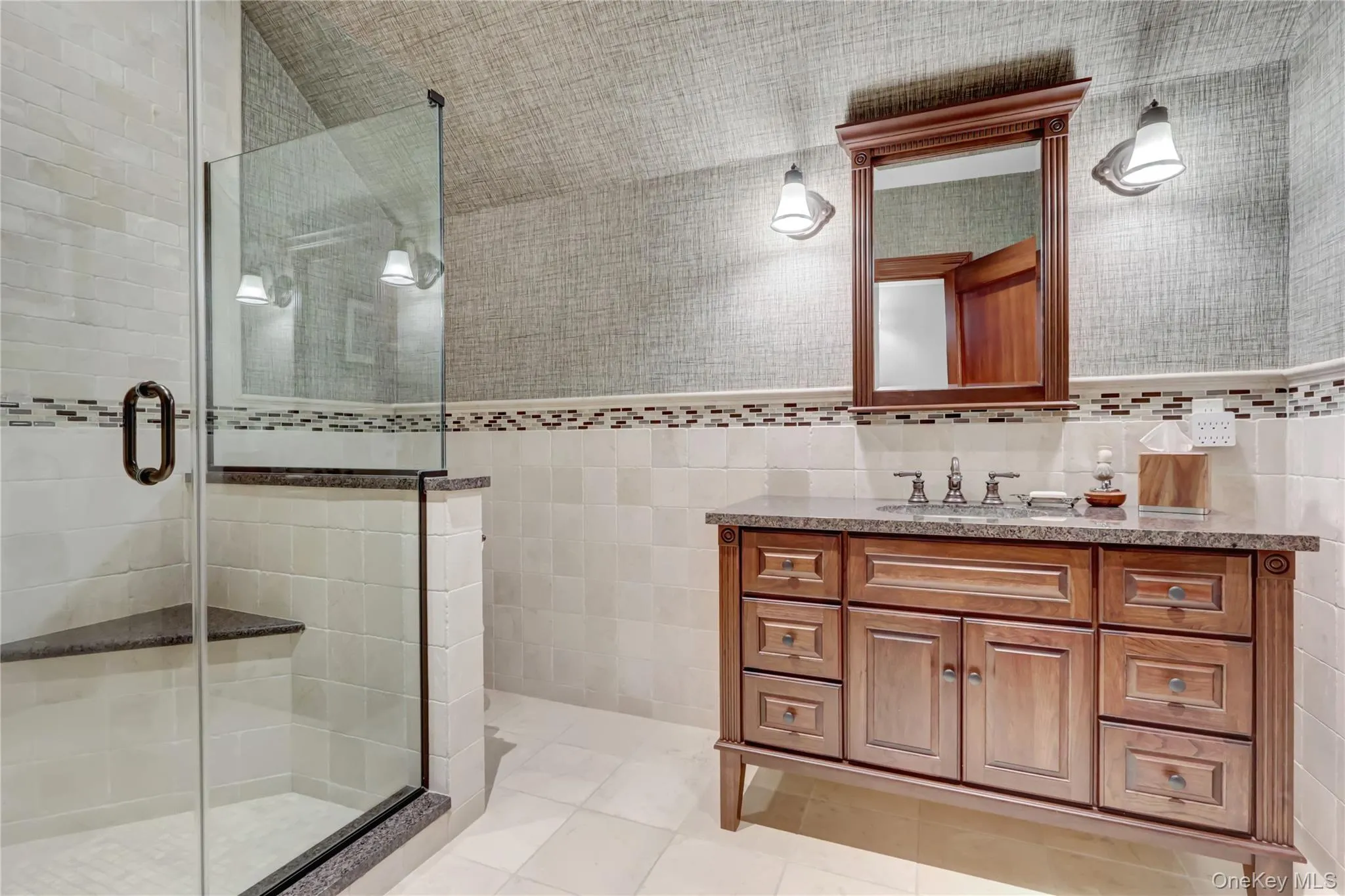 Full bathroom with tile walls, vanity, a shower stall, and light tile patterned flooring Full bathroom with tile walls, vanity, a shower stall, and light tile patterned flooring