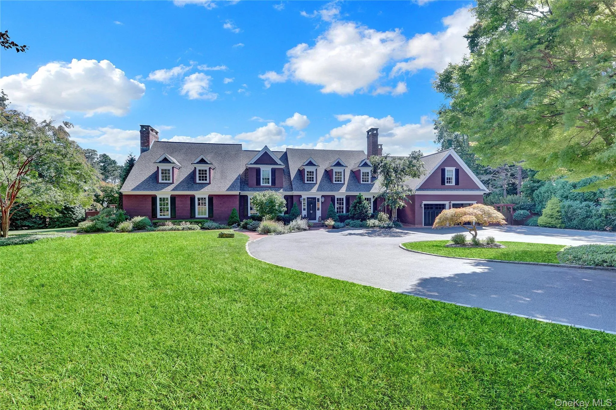 Cape cod house featuring a chimney, curved driveway, a front yard, and a garage Cape cod house featuring a chimney, curved driveway, a front yard, and a garage