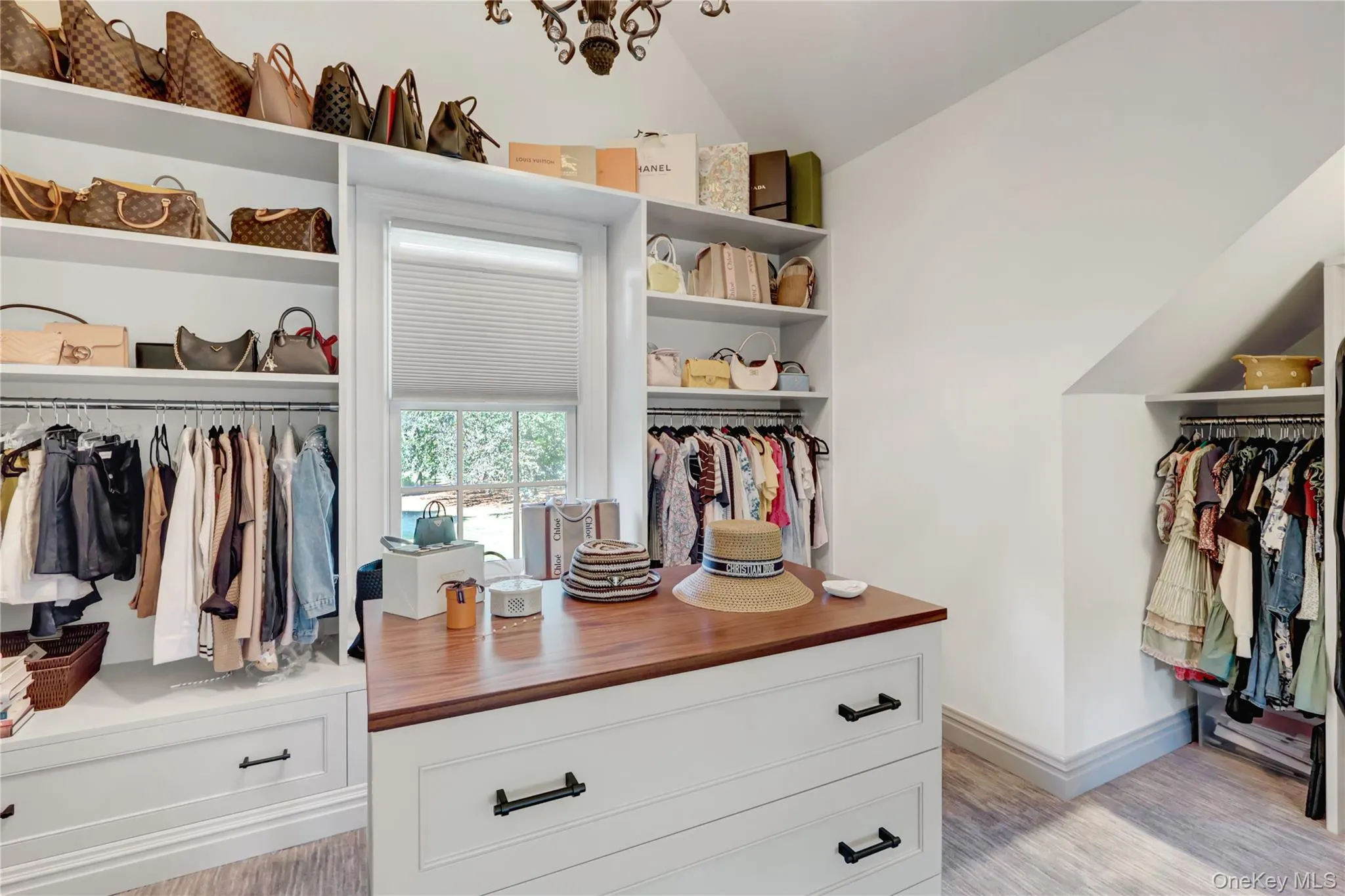 Walk in closet with lofted ceiling and light wood-style floors Walk in closet with lofted ceiling and light wood-style floors
