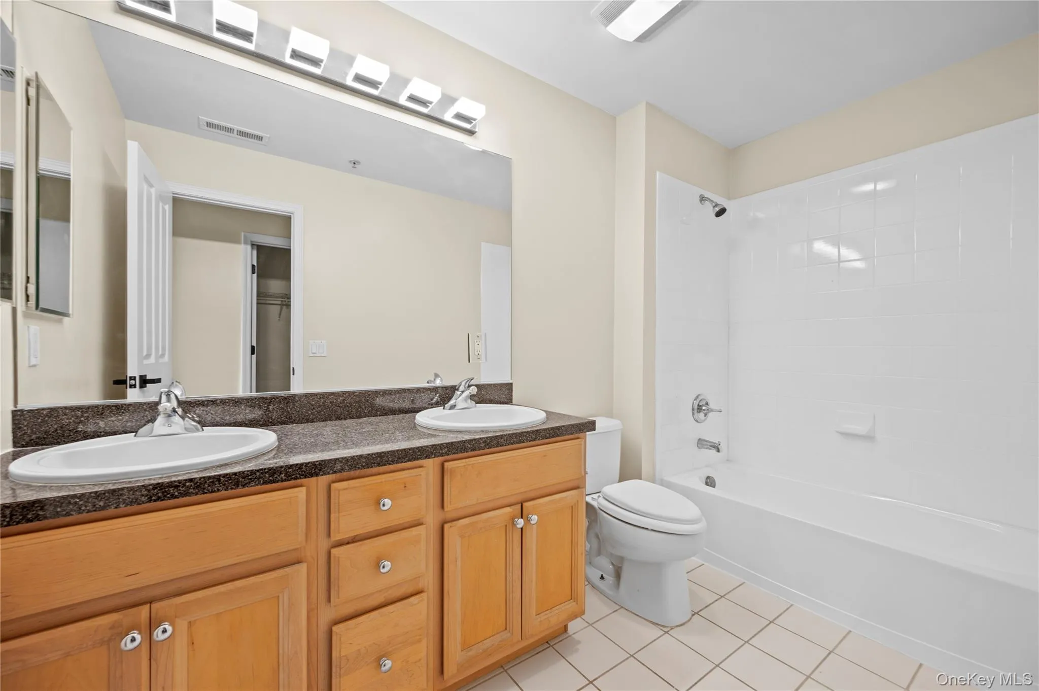 Full bathroom featuring light tile patterned floors, bathtub / shower combination, and double vanity Full bathroom featuring light tile patterned floors, bathtub / shower combination, and double vanity