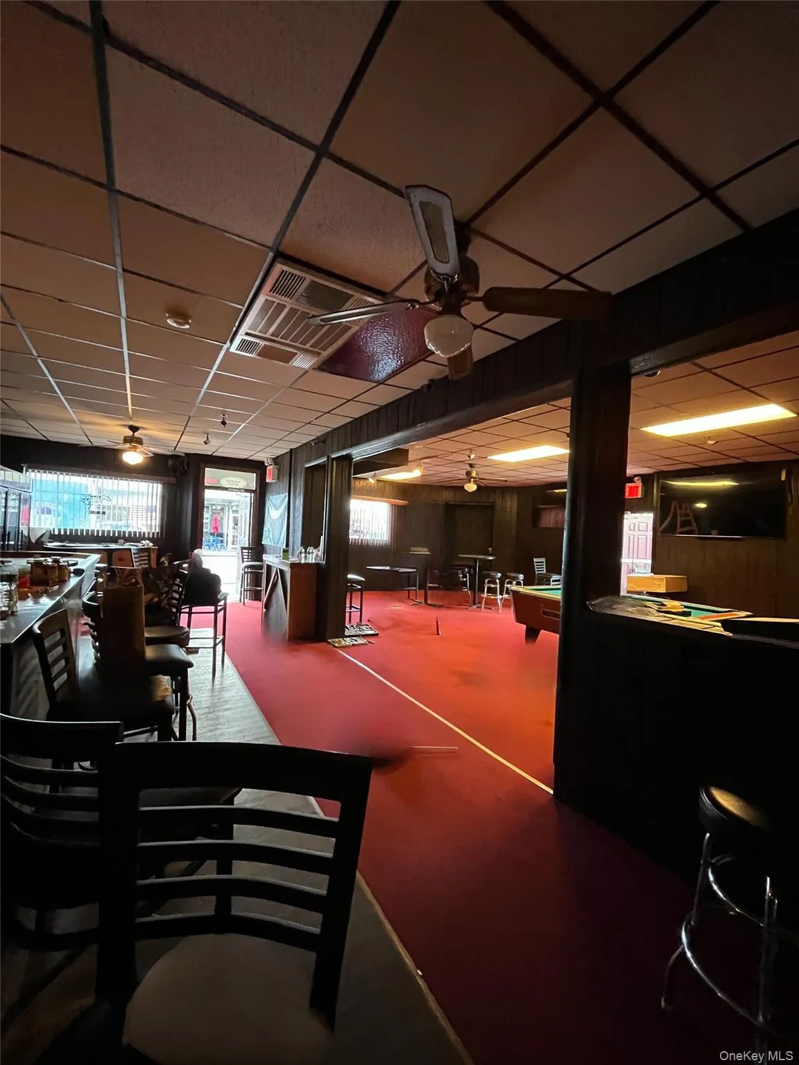 Dining area with ceiling fan, a drop ceiling, wooden walls, and billiards table Dining area with ceiling fan, a drop ceiling, wooden walls, and billiards table