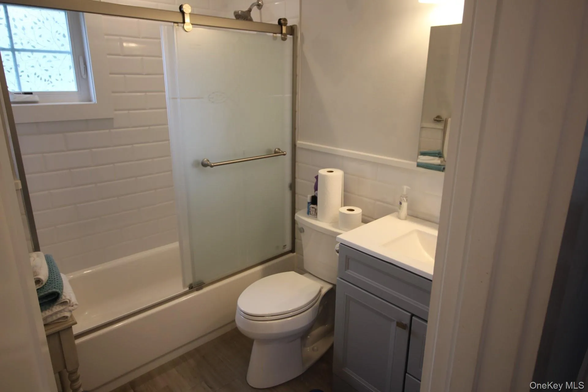 Full bathroom featuring enclosed tub / shower combo, vanity, tile walls, and decorative backsplash Full bathroom featuring enclosed tub / shower combo, vanity, tile walls, and decorative backsplash