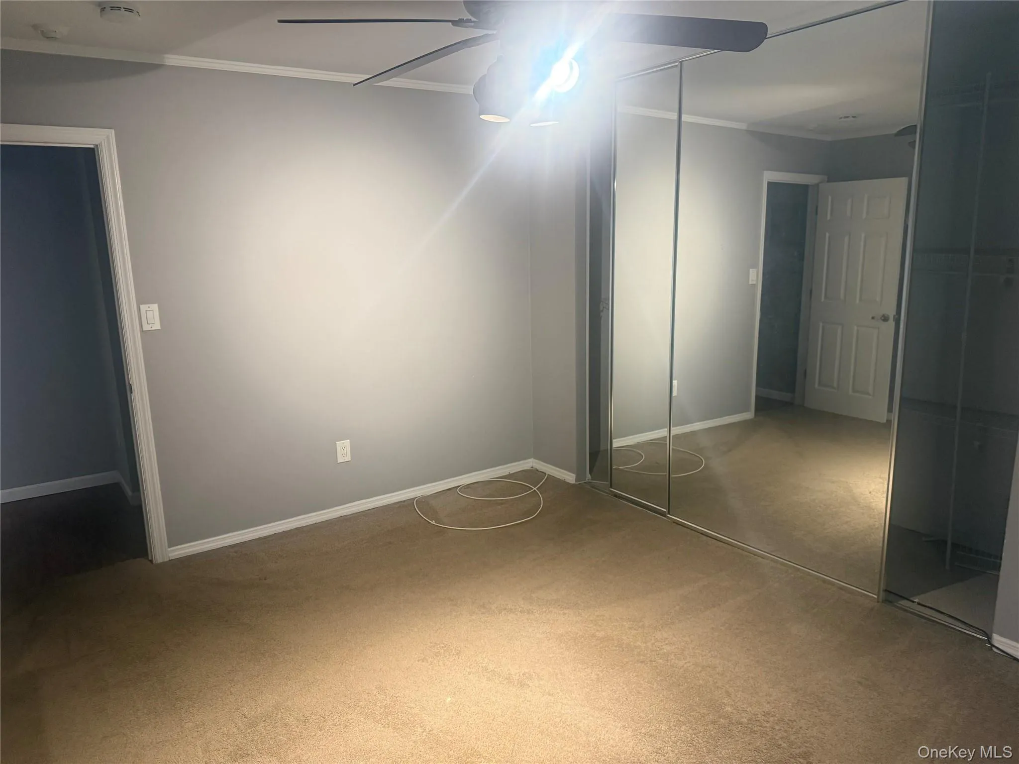 Unfurnished bedroom with crown molding, ceiling fan, and light colored carpet Unfurnished bedroom with crown molding, ceiling fan, and light colored carpet