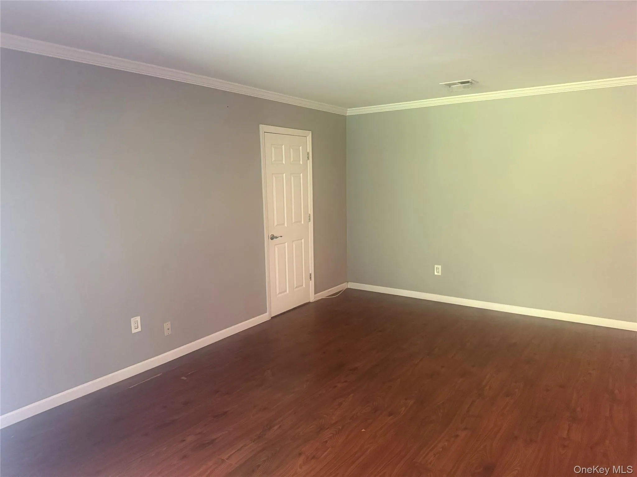 Unfurnished room featuring ornamental molding and dark wood-type flooring Unfurnished room featuring ornamental molding and dark wood-type flooring