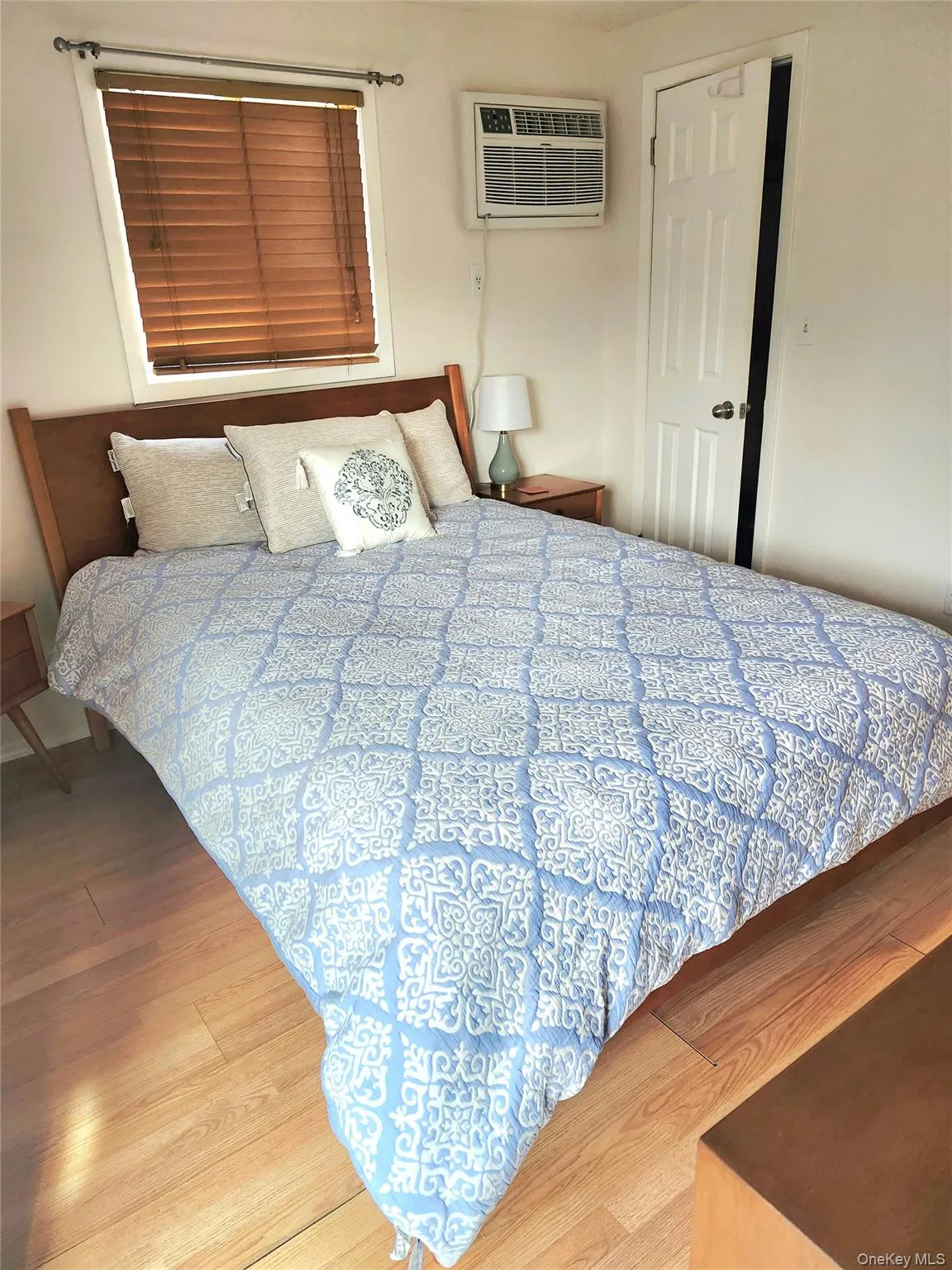 Bedroom with wood finished floors and a wall mounted air conditioner Bedroom with wood finished floors and a wall mounted air conditioner