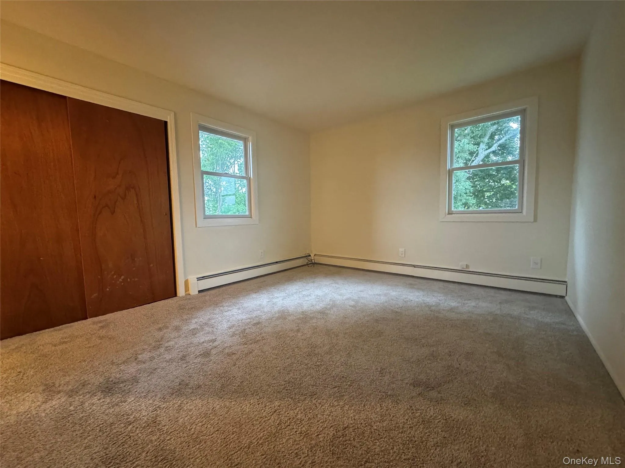 Unfurnished bedroom featuring multiple windows, carpet, and a closet Unfurnished bedroom featuring multiple windows, carpet, and a closet