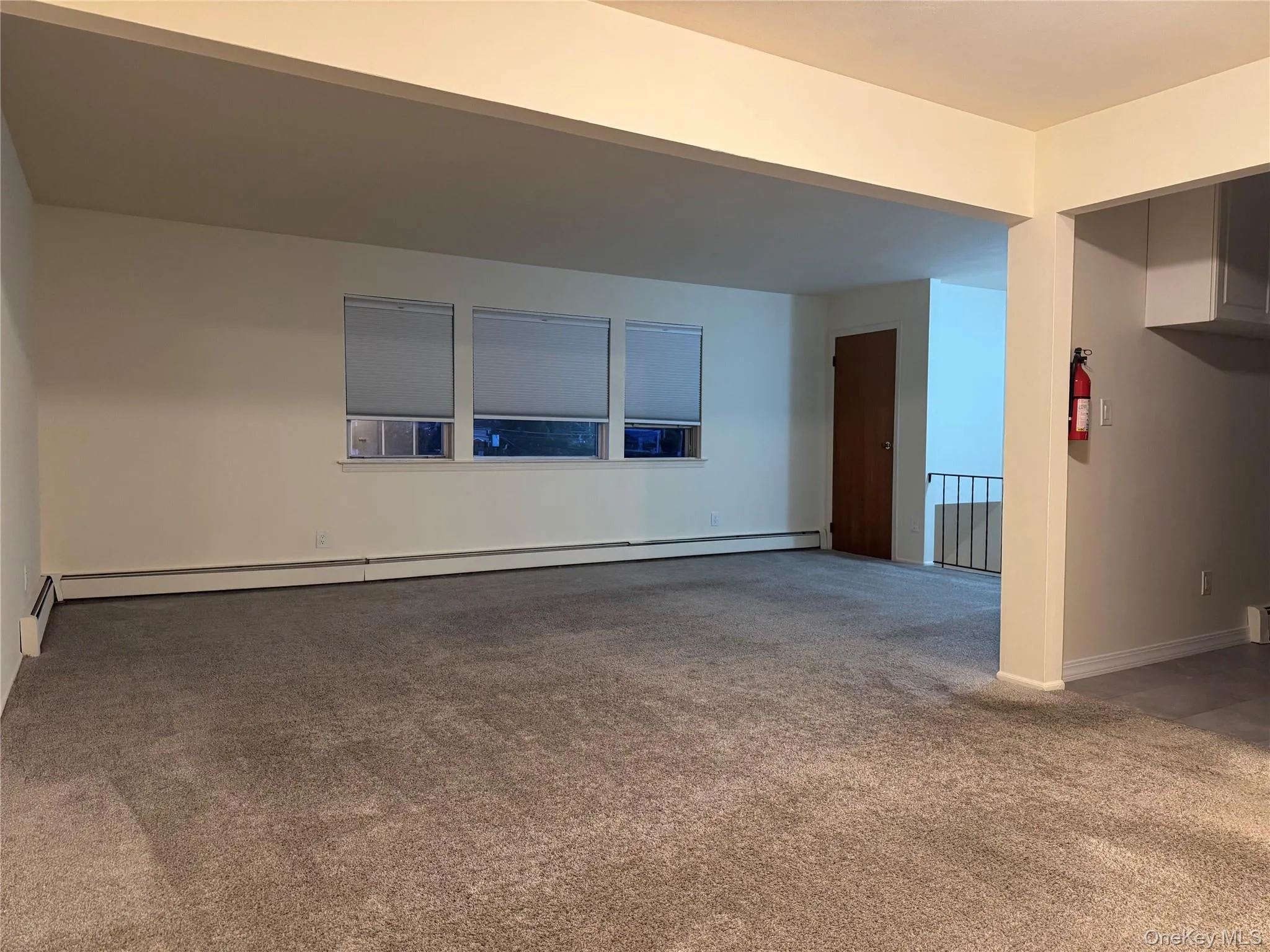 Unfurnished living room featuring light colored carpet and baseboard heating Unfurnished living room featuring light colored carpet and baseboard heating