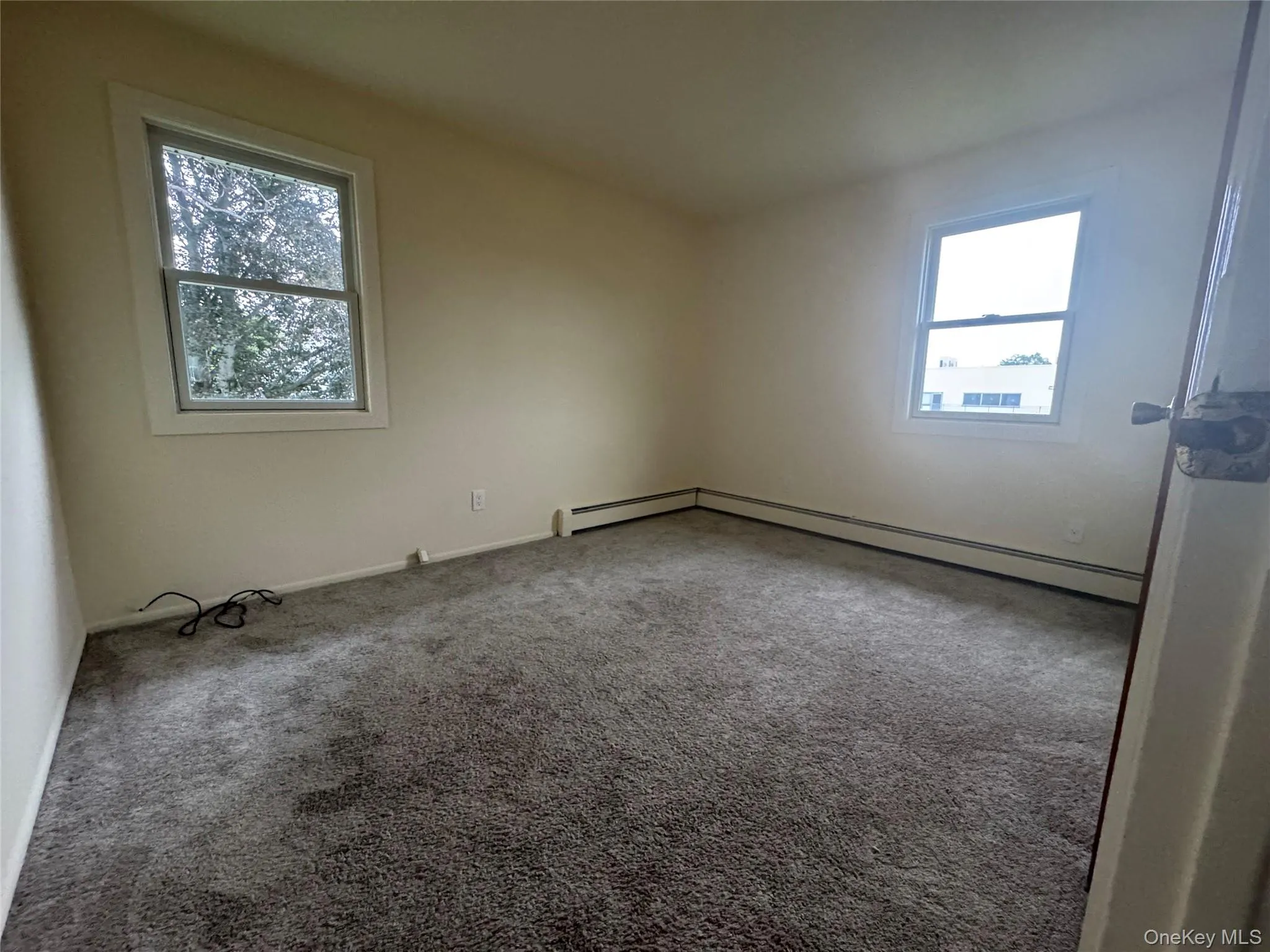 Carpeted spare room featuring a baseboard radiator and baseboards Carpeted spare room featuring a baseboard radiator and baseboards