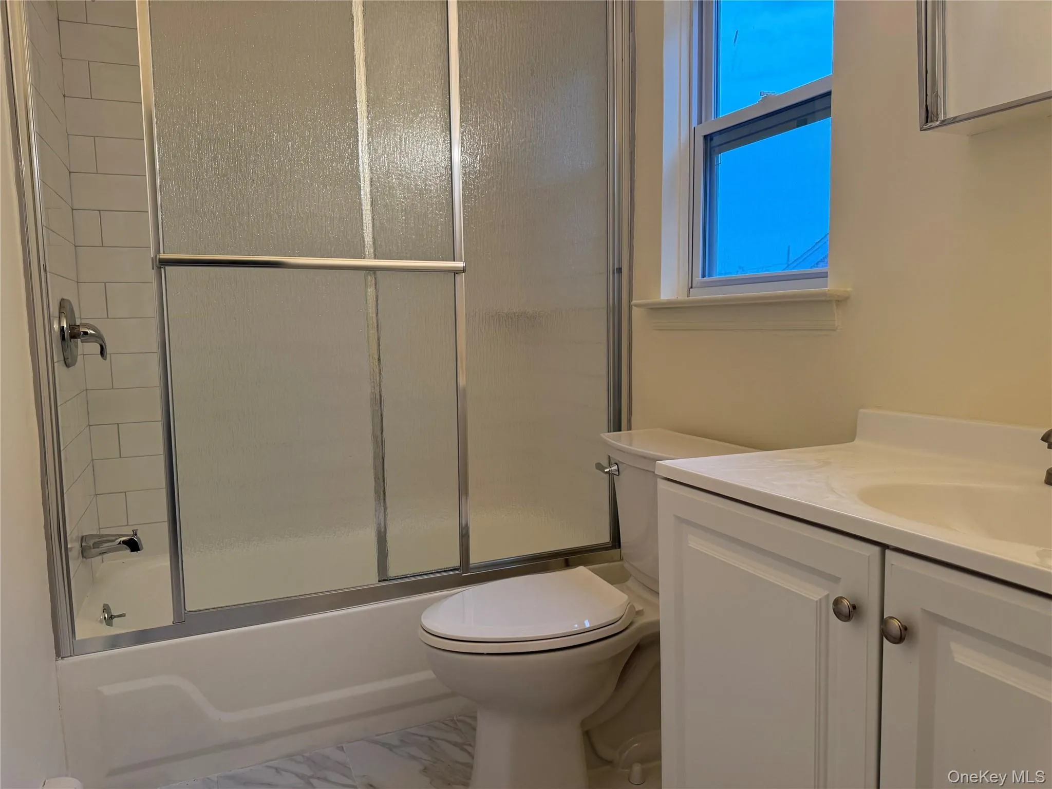 Full bath with shower / bath combination with glass door, vanity, and marble finish flooring Full bath with shower / bath combination with glass door, vanity, and marble finish flooring