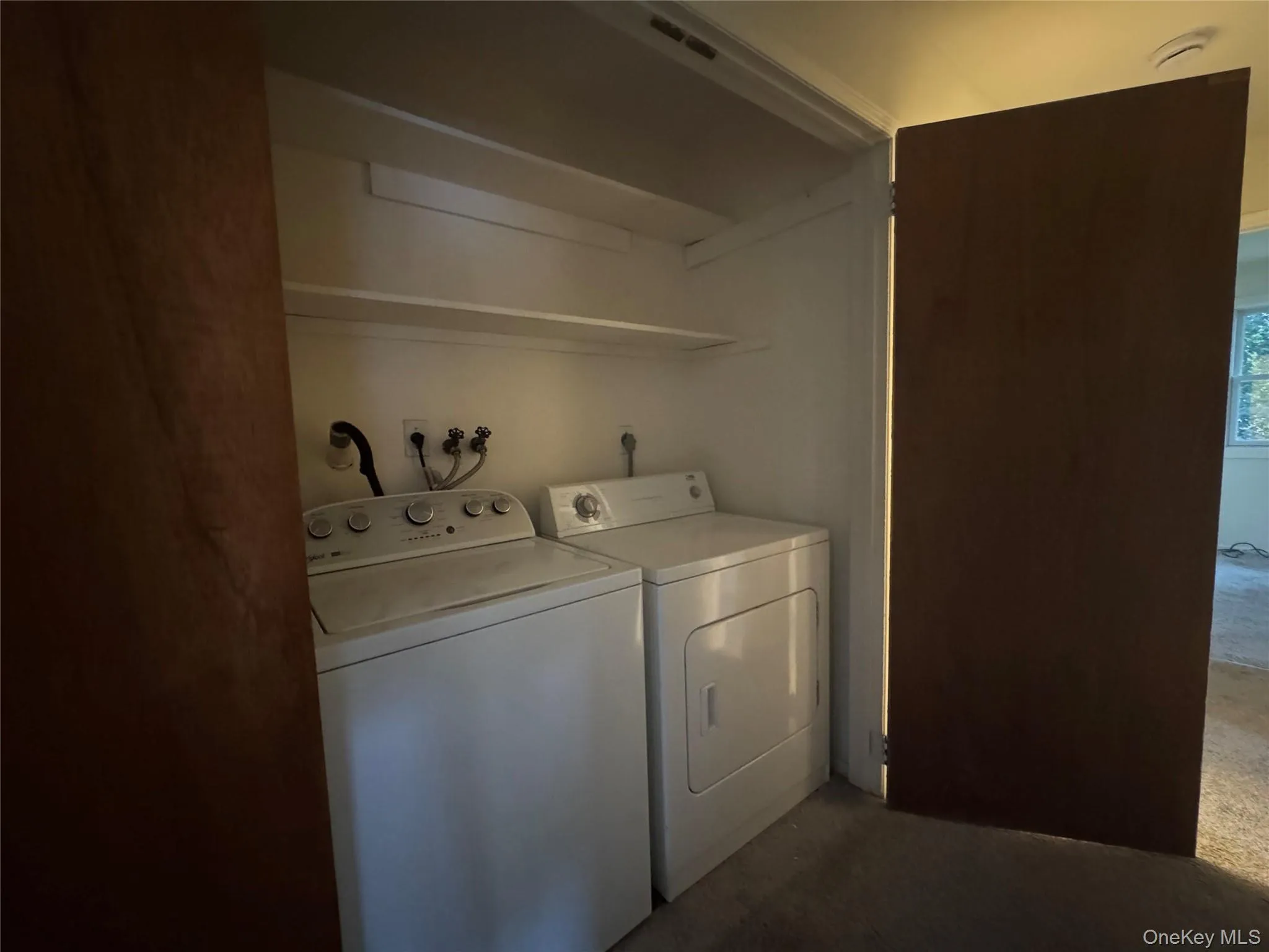 Laundry area with separate washer and dryer and dark colored carpet Laundry area with separate washer and dryer and dark colored carpet